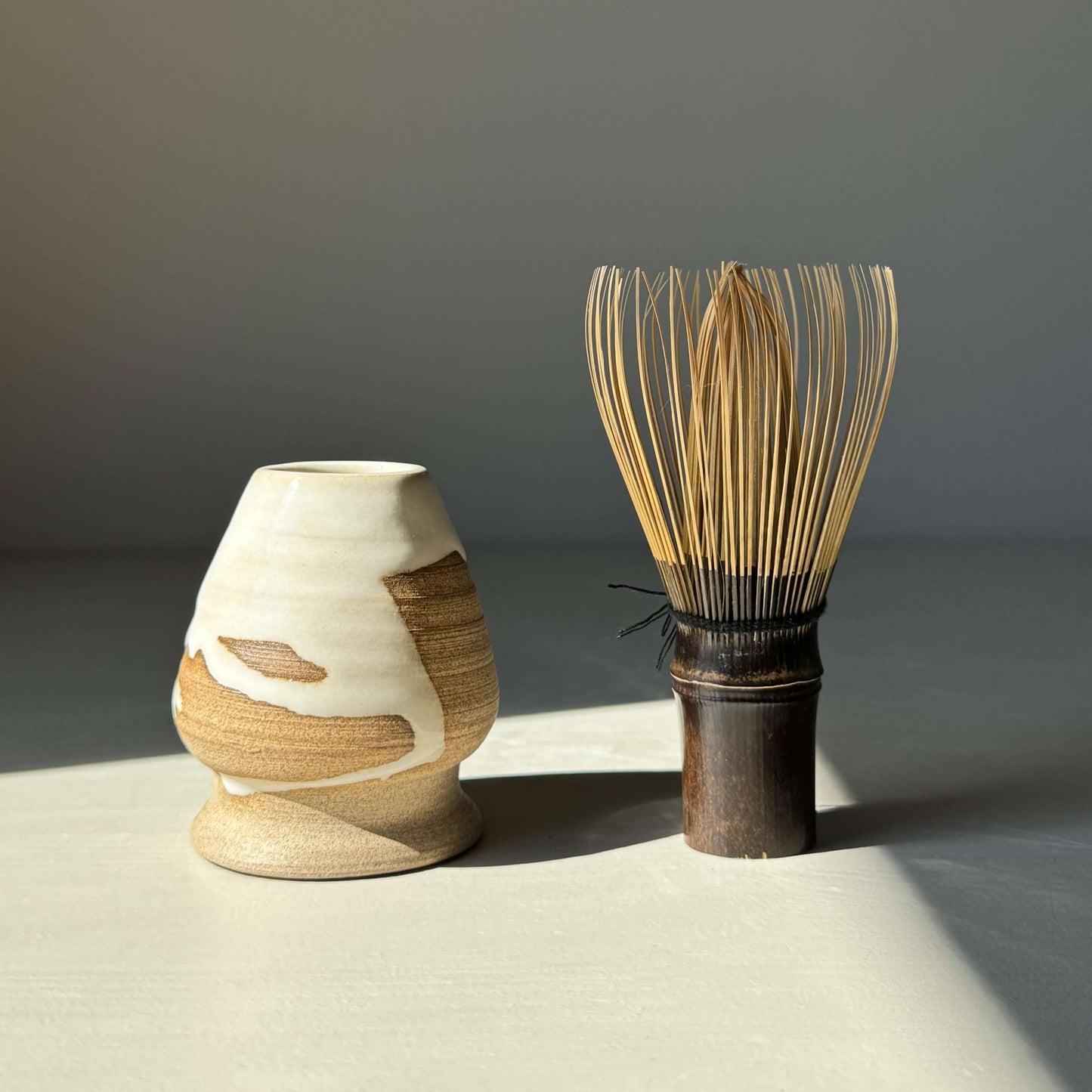 Matcha Whisk Holder from Yuki Series with bamboo whisk, featuring a glossy white glaze and natural toffee clay design.