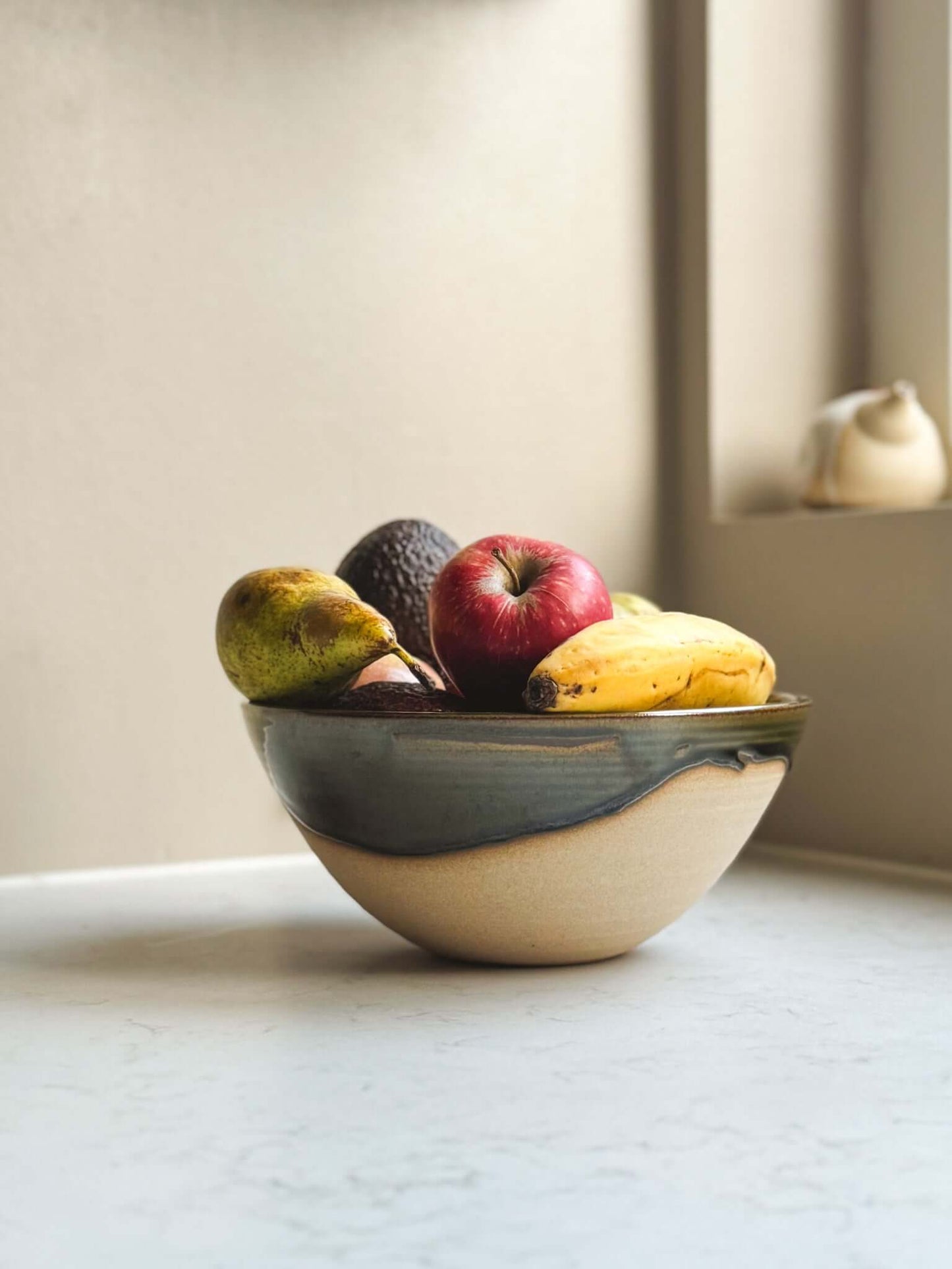 Medium Bowl - Mori #02 with green glaze, holding fruit on a white countertop