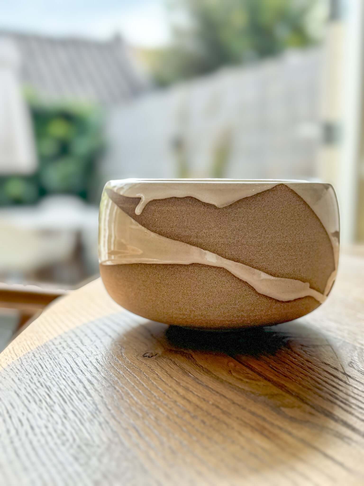 Medium Bowl - Yuki #01 handmade ceramic with white glaze over toffee clay, displaying flowing patterns on a wooden surface.