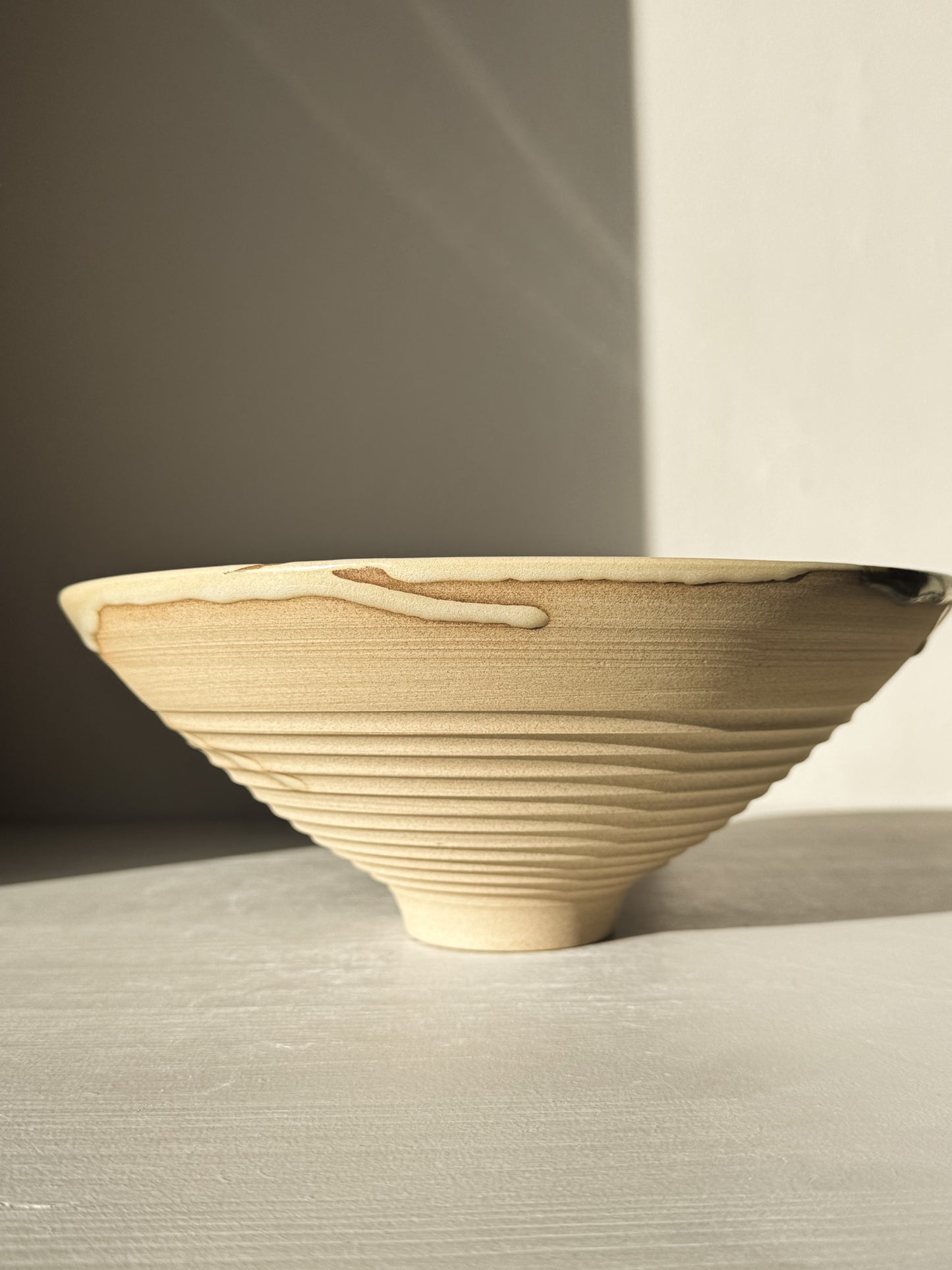 Medium Carved Bowl - Inyo #02 with sculptural carved exterior and flowing glaze drips on raw clay surface, side view.