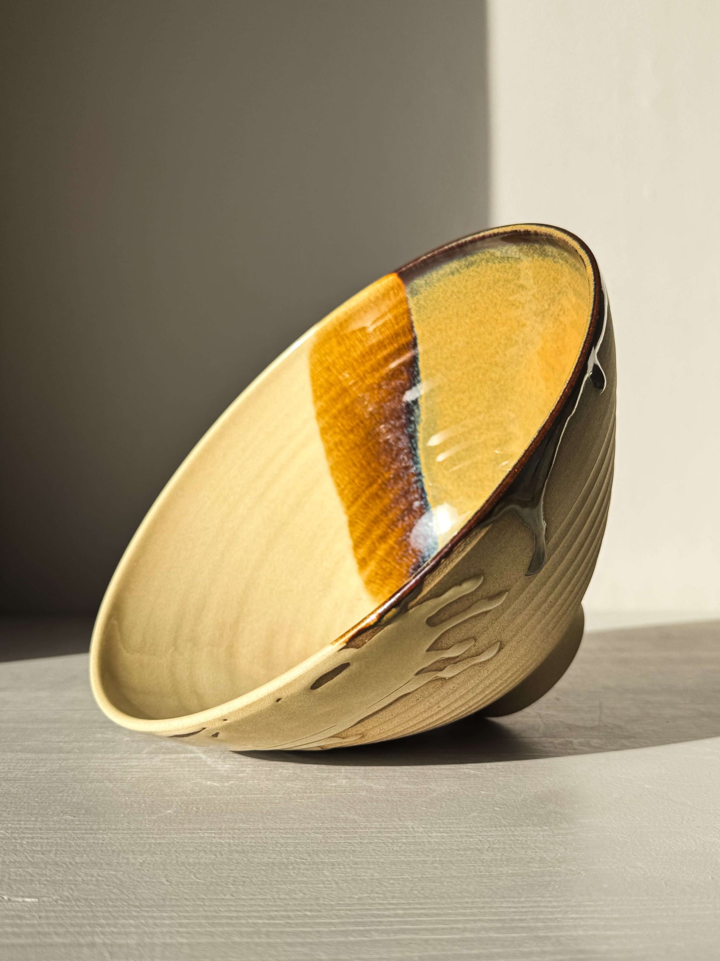 Medium Carved Bowl - Inyo #01 with golden, brown, and blue tones, carved exterior, and drip details on the rim in sunlight.