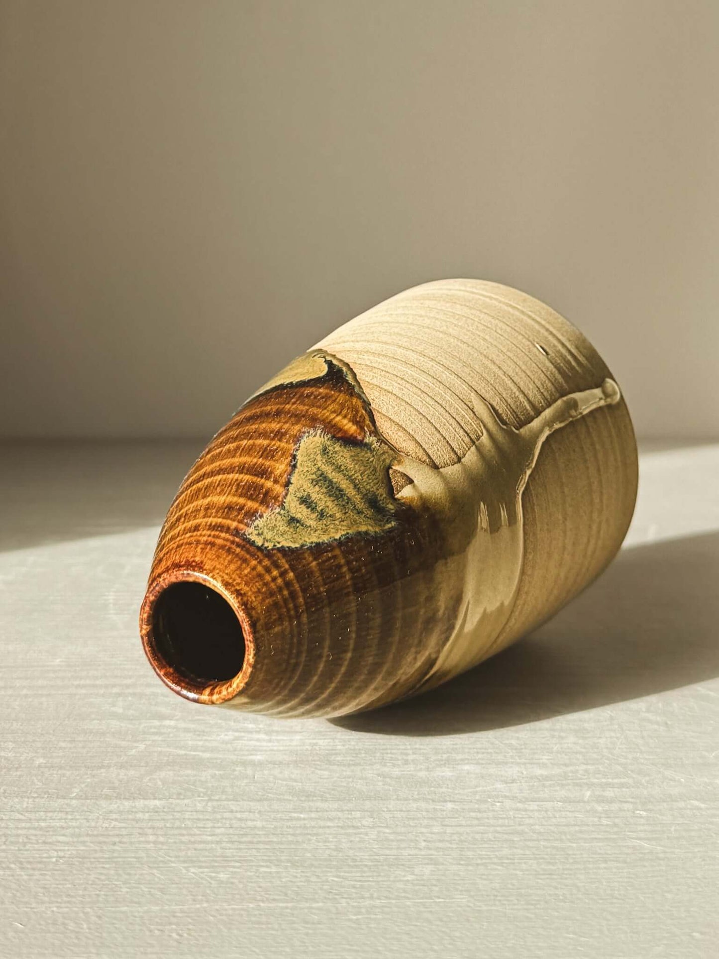 Medium Vase – Inyo #02 with tenmoku glaze, tall and rounded with a narrow opening, on a light surface.