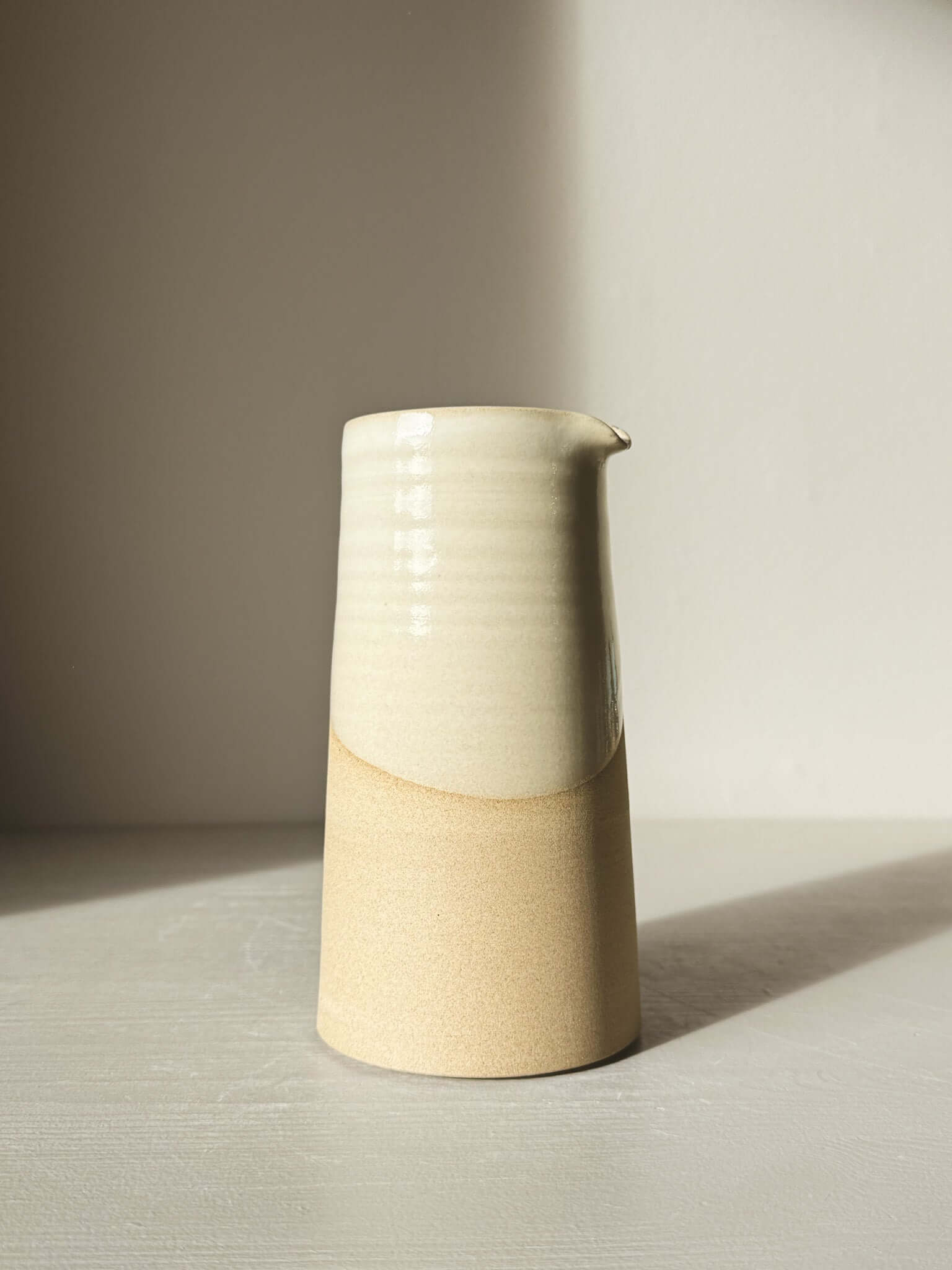 Medium Vase/Jug – Yuki #02, tall sculptural piece with glossy white glaze contrasted by warm toffee-colored clay base, elegant design.