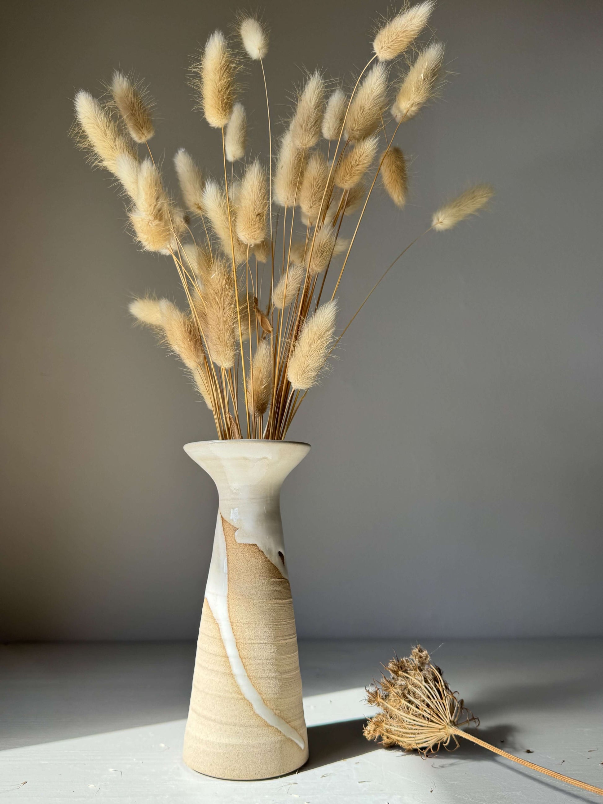 Medium Vase – Yuki #02 handmade ceramic with dried grasses, showcasing graceful white glaze flow on warm stoneware surface.