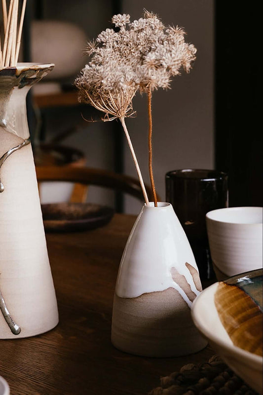 Medium Vase – Yuki #04 with dry flowers on a wooden table, showcasing its elegant, glossy white glaze and smooth curves.