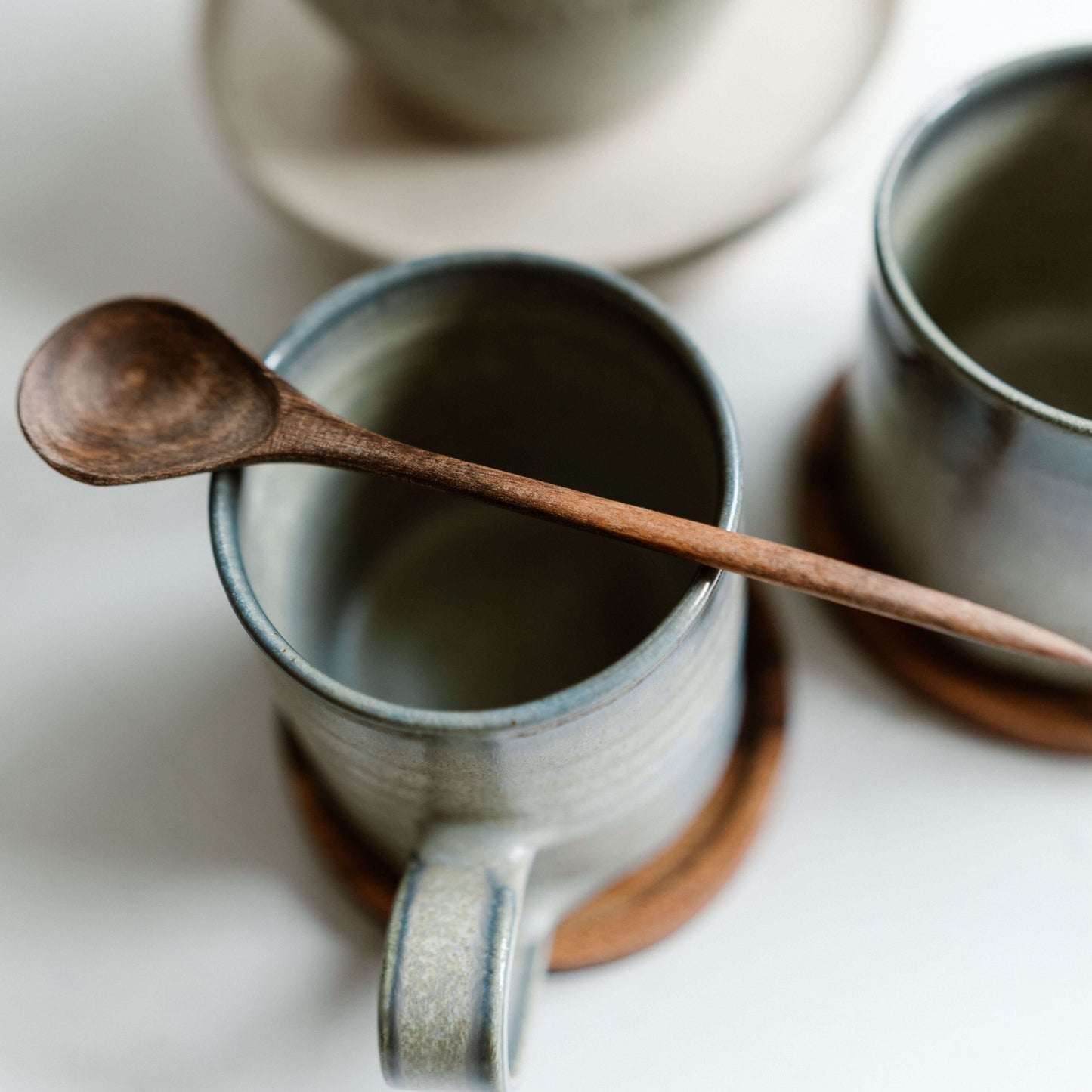 Medium Walnut Wooden Spoons resting on handmade ceramic cups, perfect for coffee or yogurt.