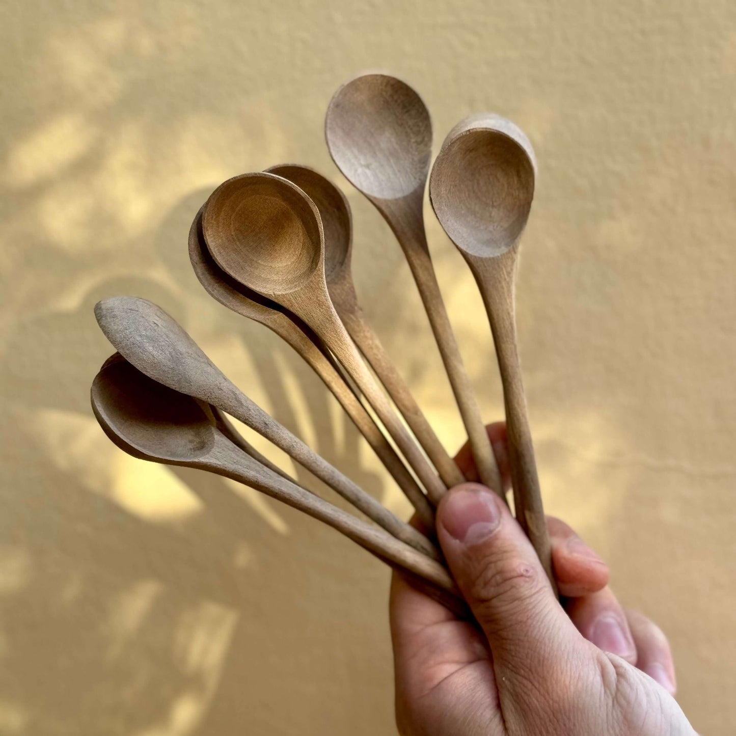 Hand holding medium wooden spoons handmade in Marrakech