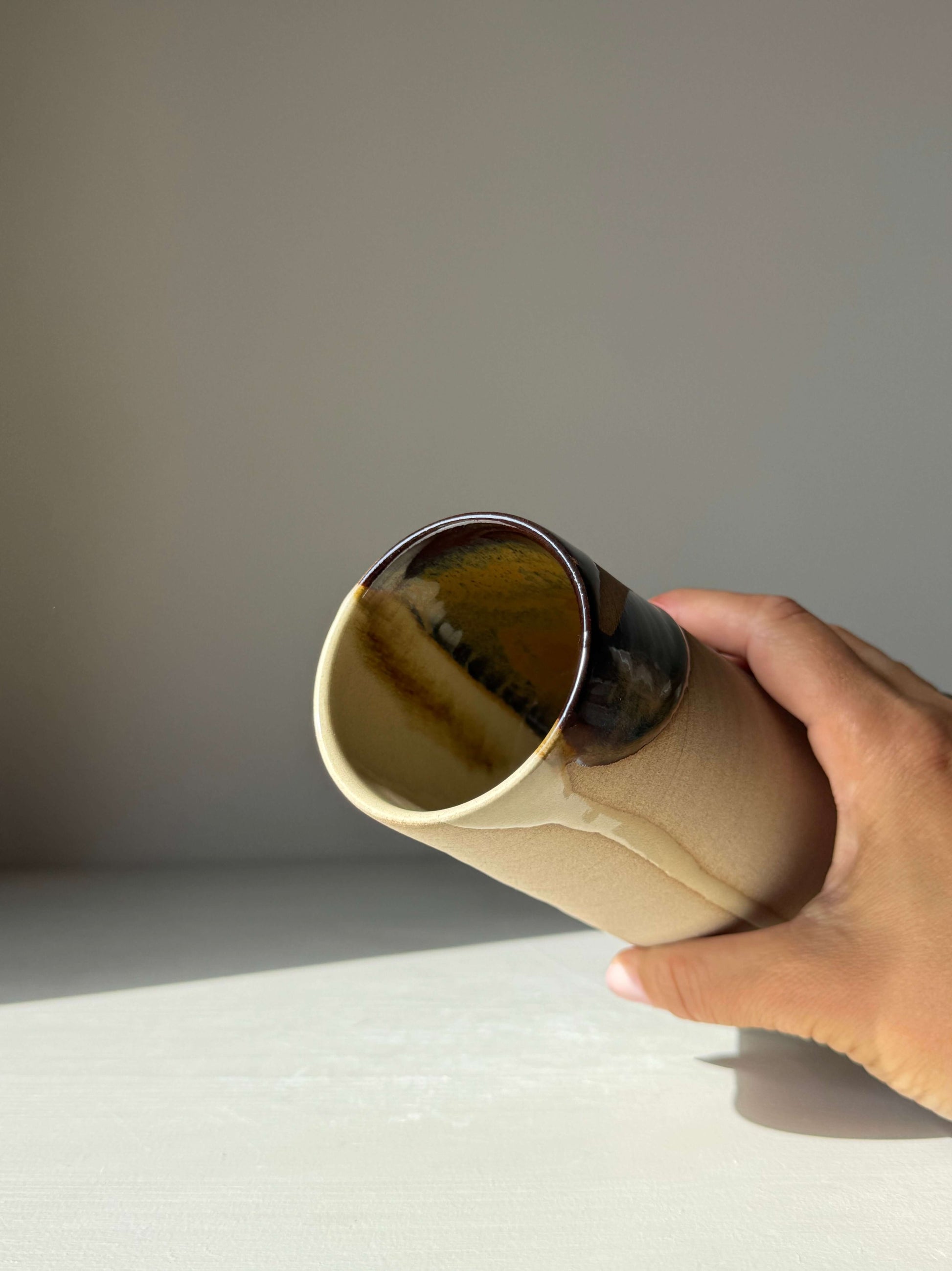 Hand holding Medium Vase - Inyo Series, handmade ceramic with tenmoku glaze, showcasing raw texture and flowing glaze contrast.