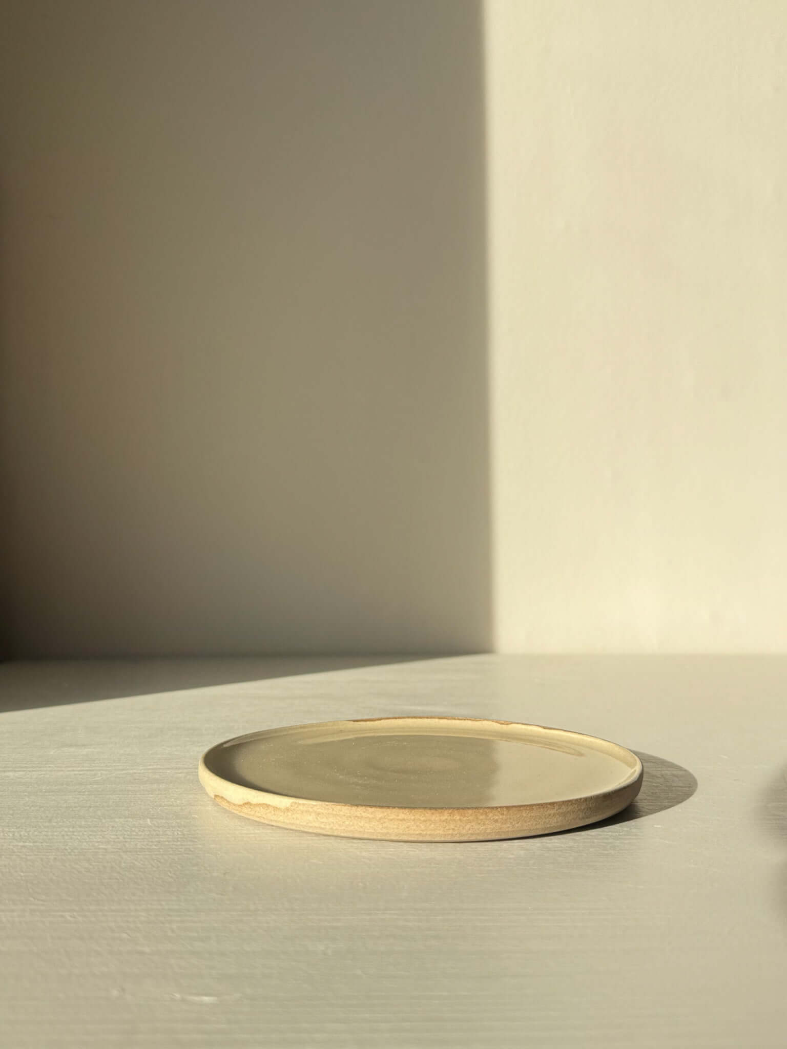 Minimalist ceramic plate with beige and cream tones on a light surface