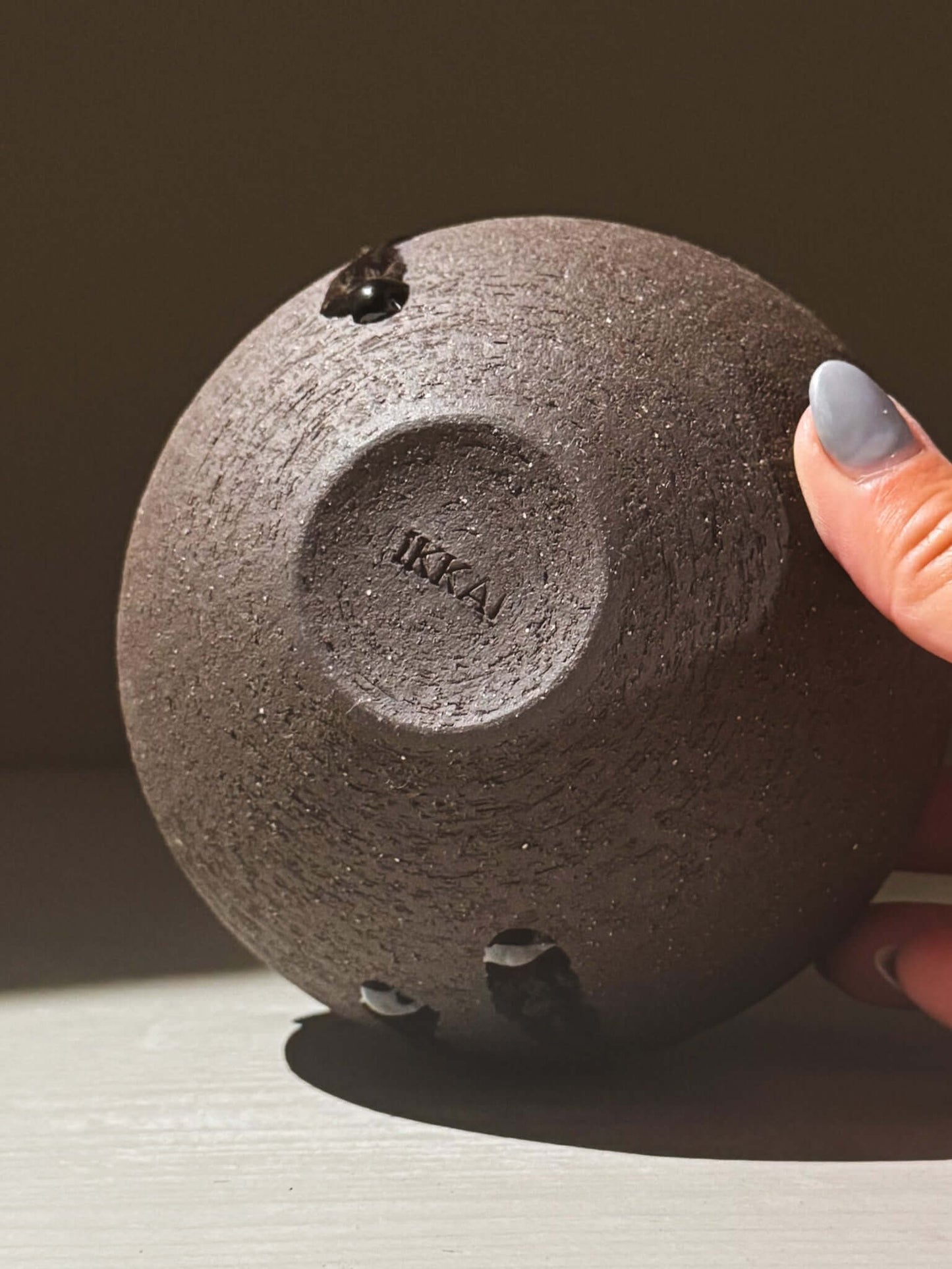 Bottom view of Orb Vase – Kuro Black #02 showing texture and IKKA logo, highlighting unique clay and glaze of the collection.