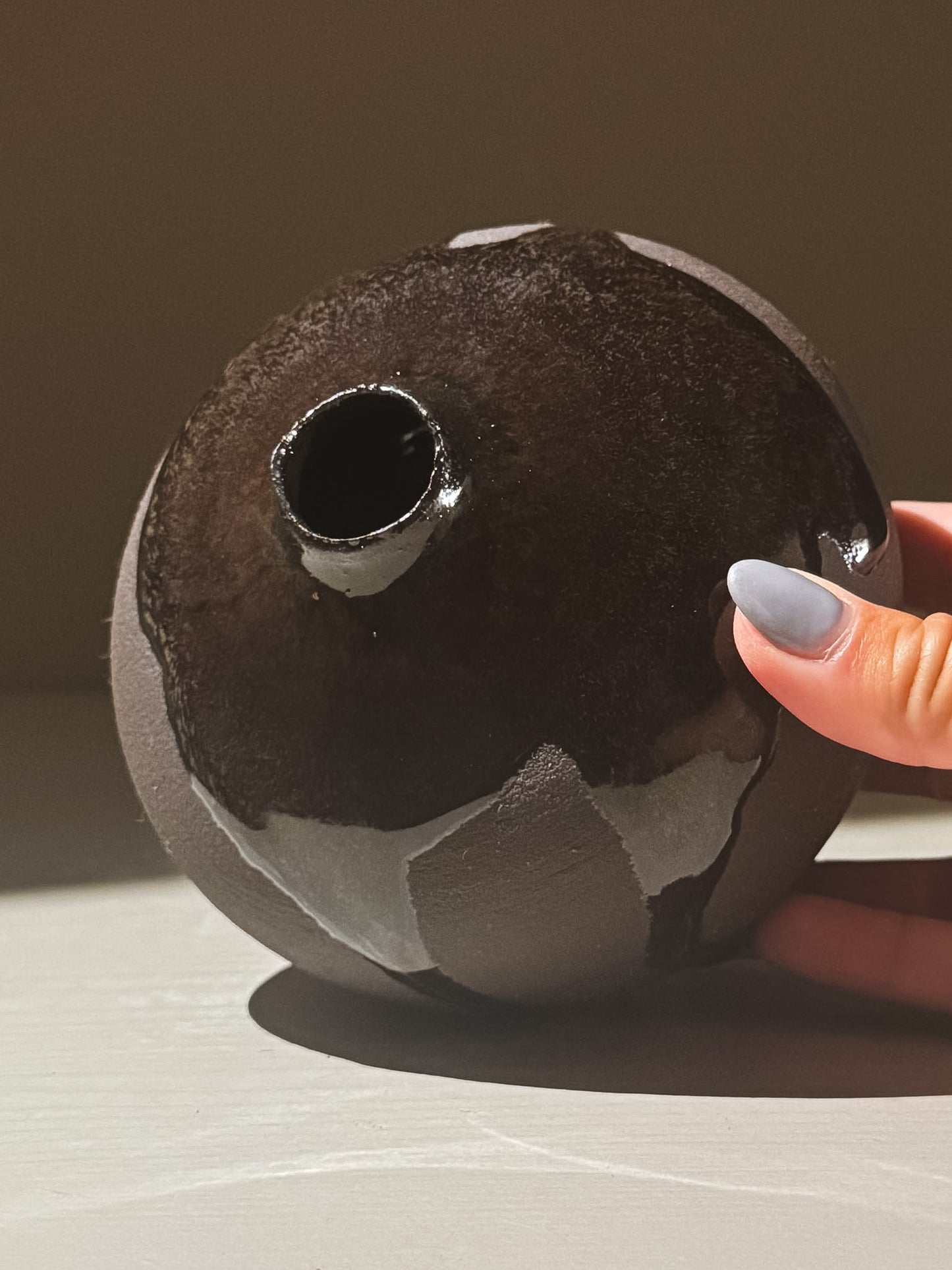 Orb Vase – Kuro Black #02 with unique glaze patterns and soft spherical form, held in hand.