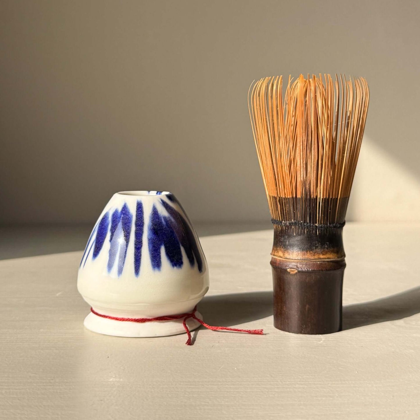 Porcelain Whisk Holder – Cobalt & Gold Lustre next to bamboo matcha whisk on a neutral surface.
