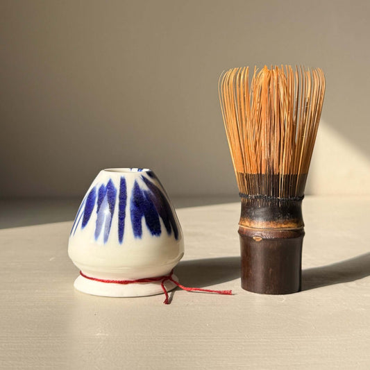 Porcelain Whisk Holder – Cobalt & Gold Lustre next to bamboo matcha whisk on a neutral surface.