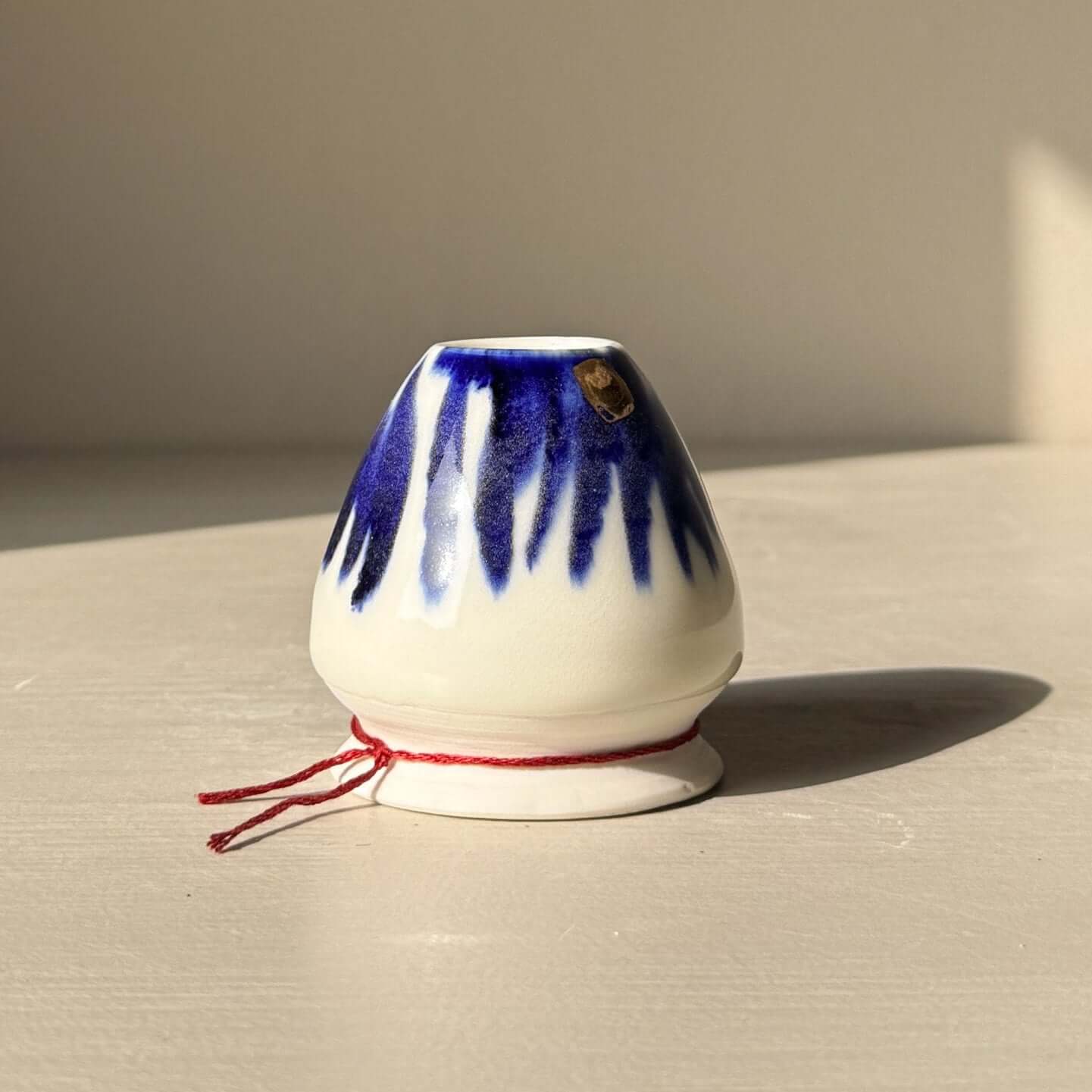 Small ceramic porcelein matcha whisk holder with blue patterns on a white surface