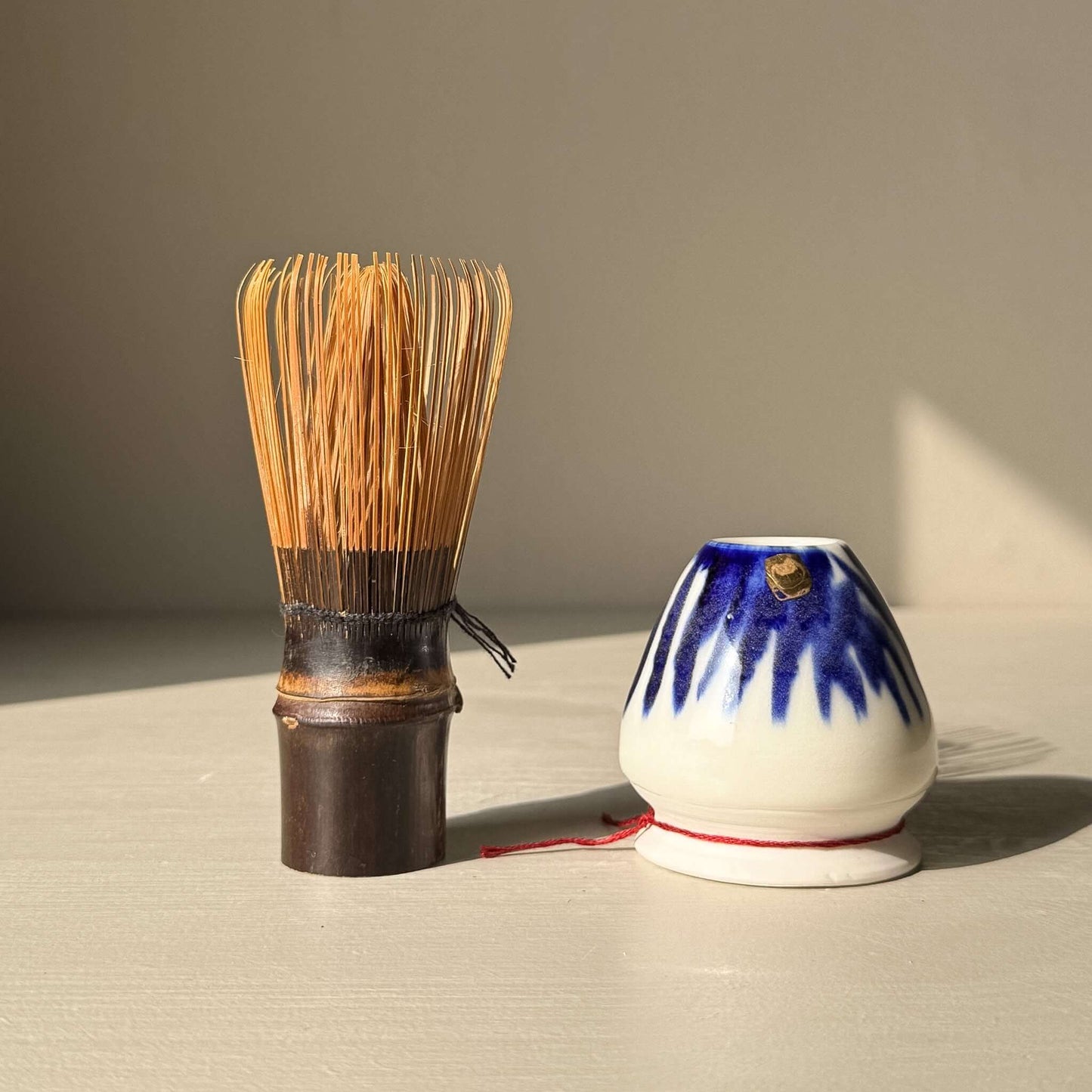 Porcelain Whisk Holder – Cobalt & Gold Lustre alongside a bamboo matcha whisk (chasen) on a light surface.