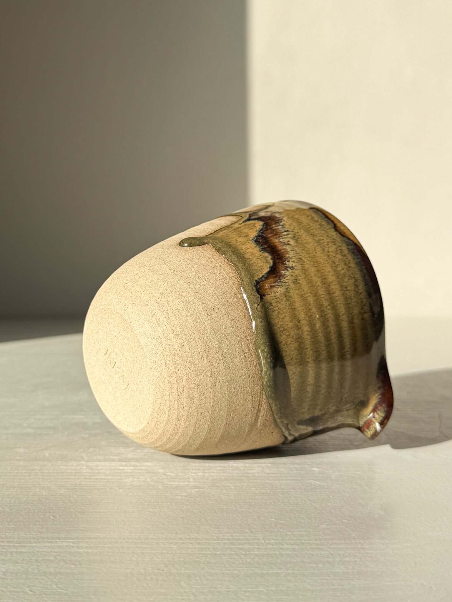 Handmade ceramic Pouring Jug – Inyo Series #01 with glossy tenmoku and clear glaze over toffee clay lying on its side.