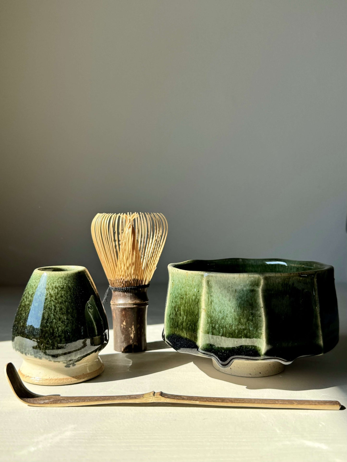 Matcha tea set with premium Takayama Chasen, dark bamboo whisk, green tea bowls, and a bamboo spoon on a light background.