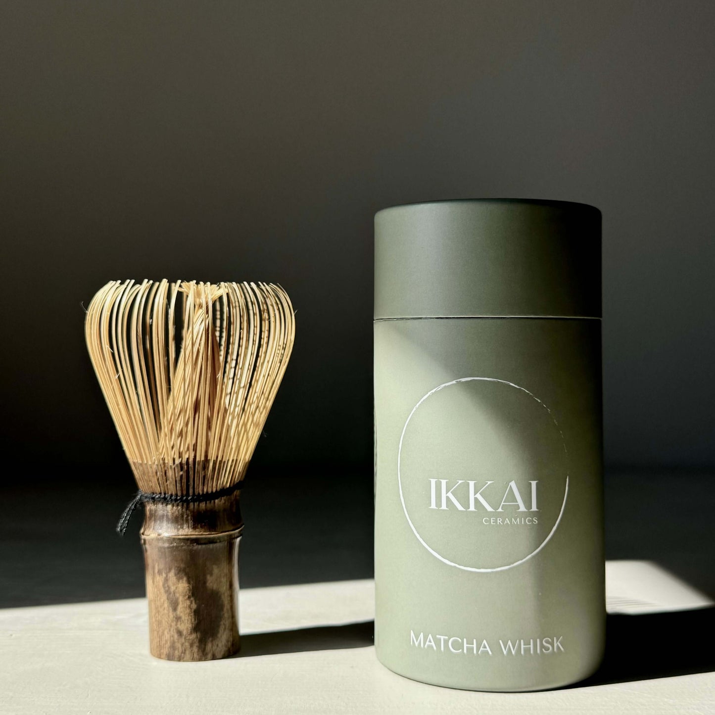 Premium Takayama Chasen dark bamboo matcha whisk next to green packaging, perfect for making creamy matcha tea froth.