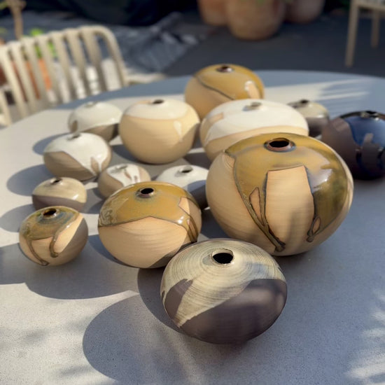 Orb Vase – Tenmoku #02 collection of unique rounded vases with natural glaze patterns on a table.