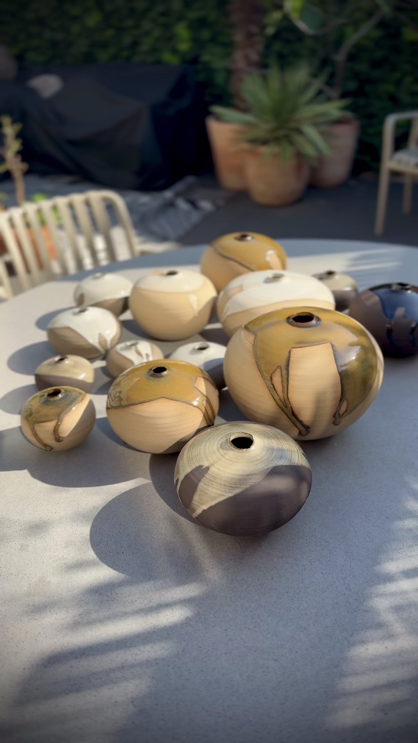 A collection of unique Orb Vase – Kuro #0 displayed on a table, showcasing different sizes and glaze patterns.