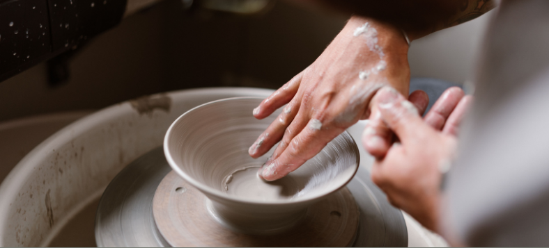 Close-up of hands shaping clay on a pottery wheel at IKKAI Ceramics