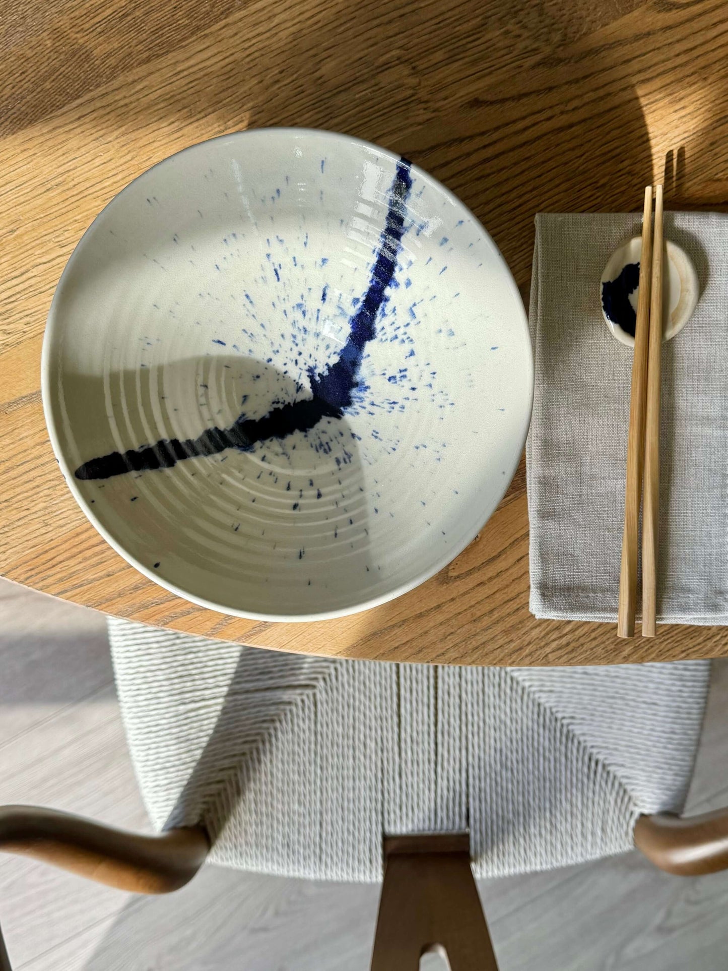 Handcrafted Gosu Series Ramen Bowl with deep cobalt splash on a dining table next to chopsticks, inspired by Japanese aesthetics.