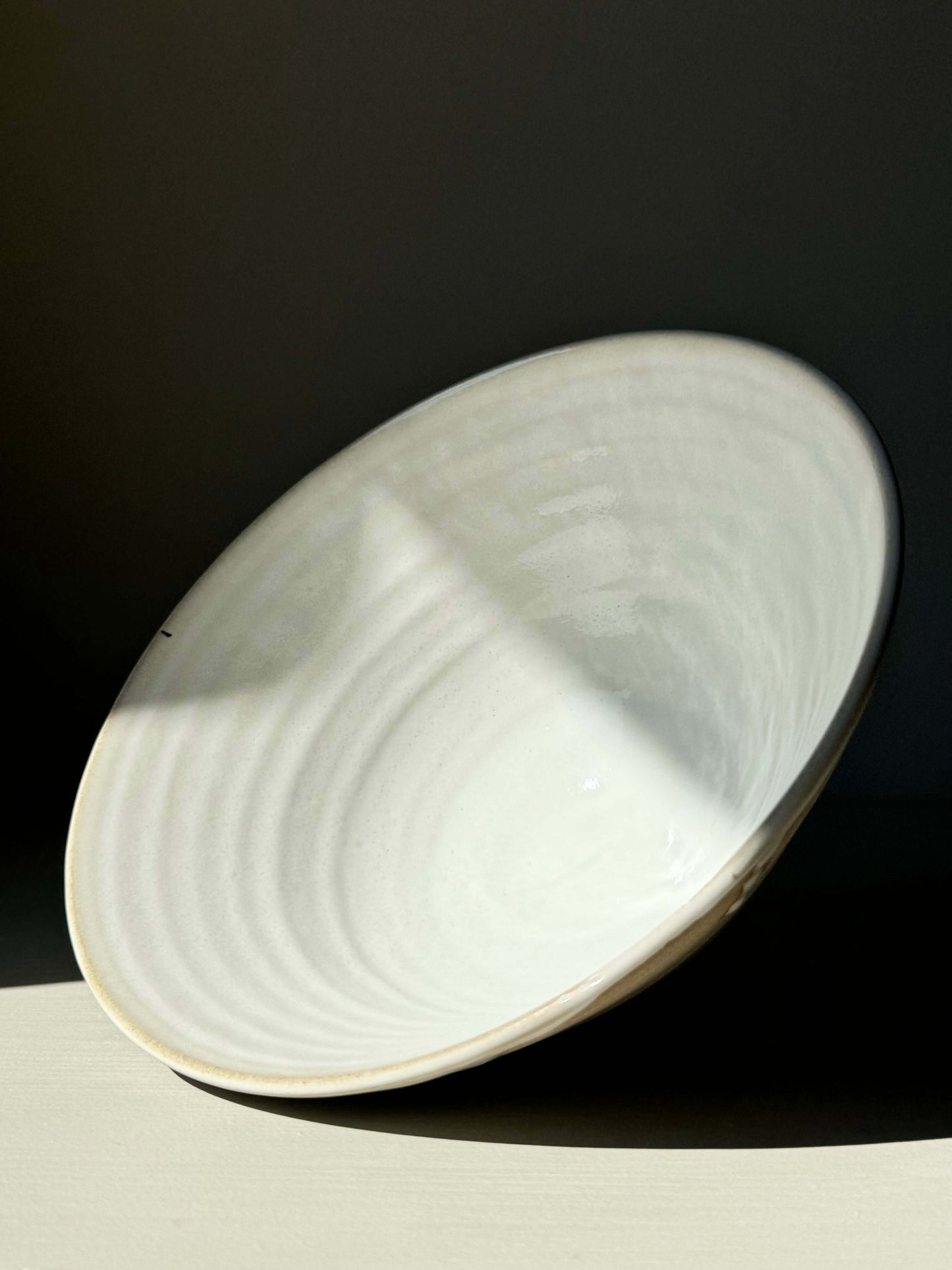 Glossy white Yuki Series ramen bowl with soft rounded shape and raw toffee clay exterior, resting on surface.