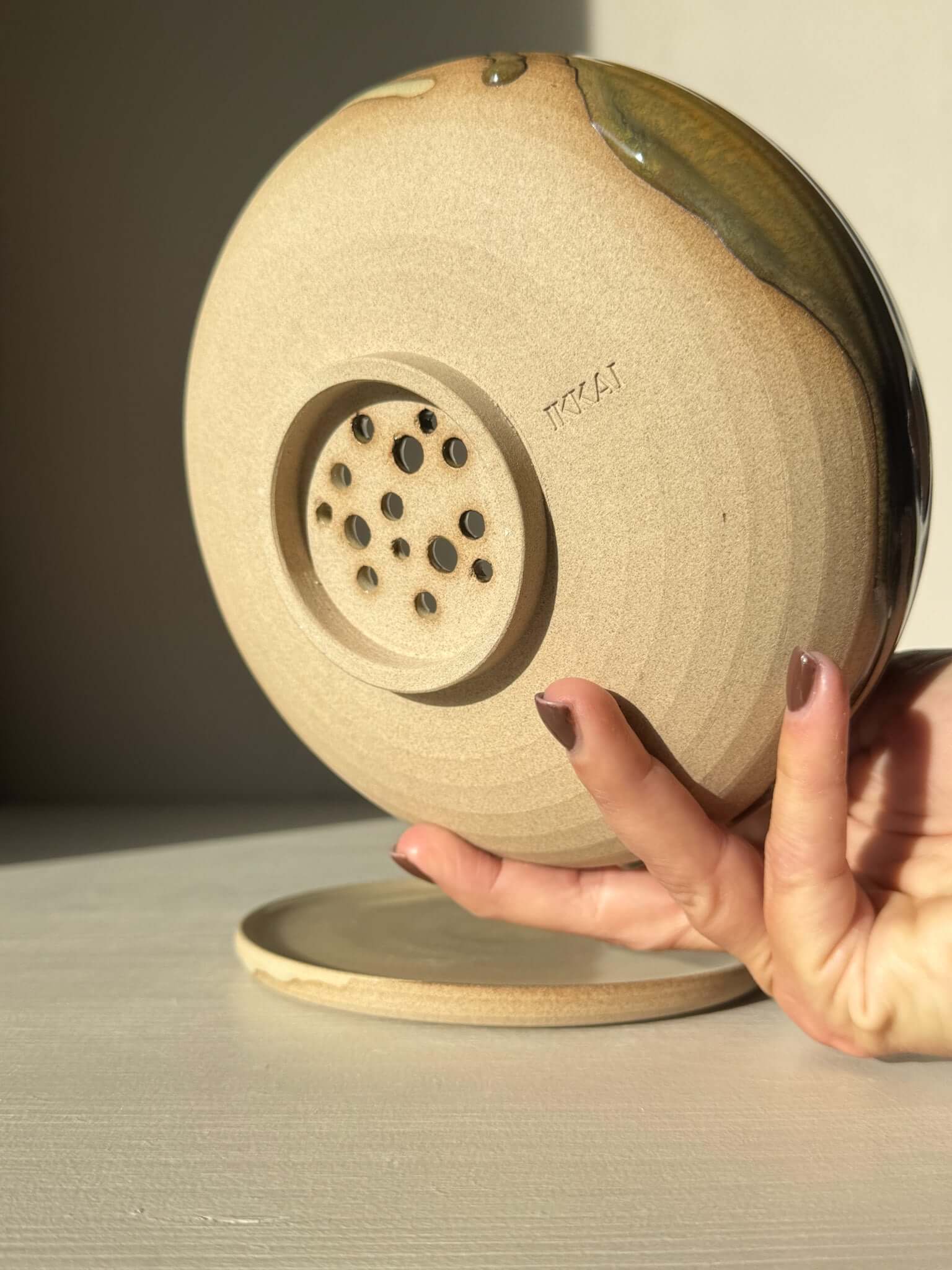 Back view of Rounded Berry Bowl - Inyo #02 with matching drip plate, showcasing its drainage design in soft morning light.