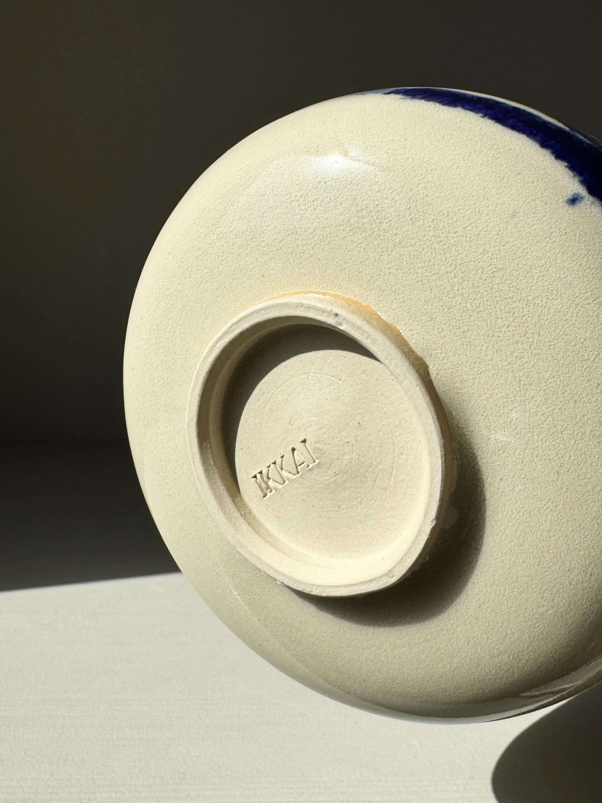 Base of Rounded Matcha Bowl, Gosu Series #02, showing indigo glaze and stamped signature in soft lighting.