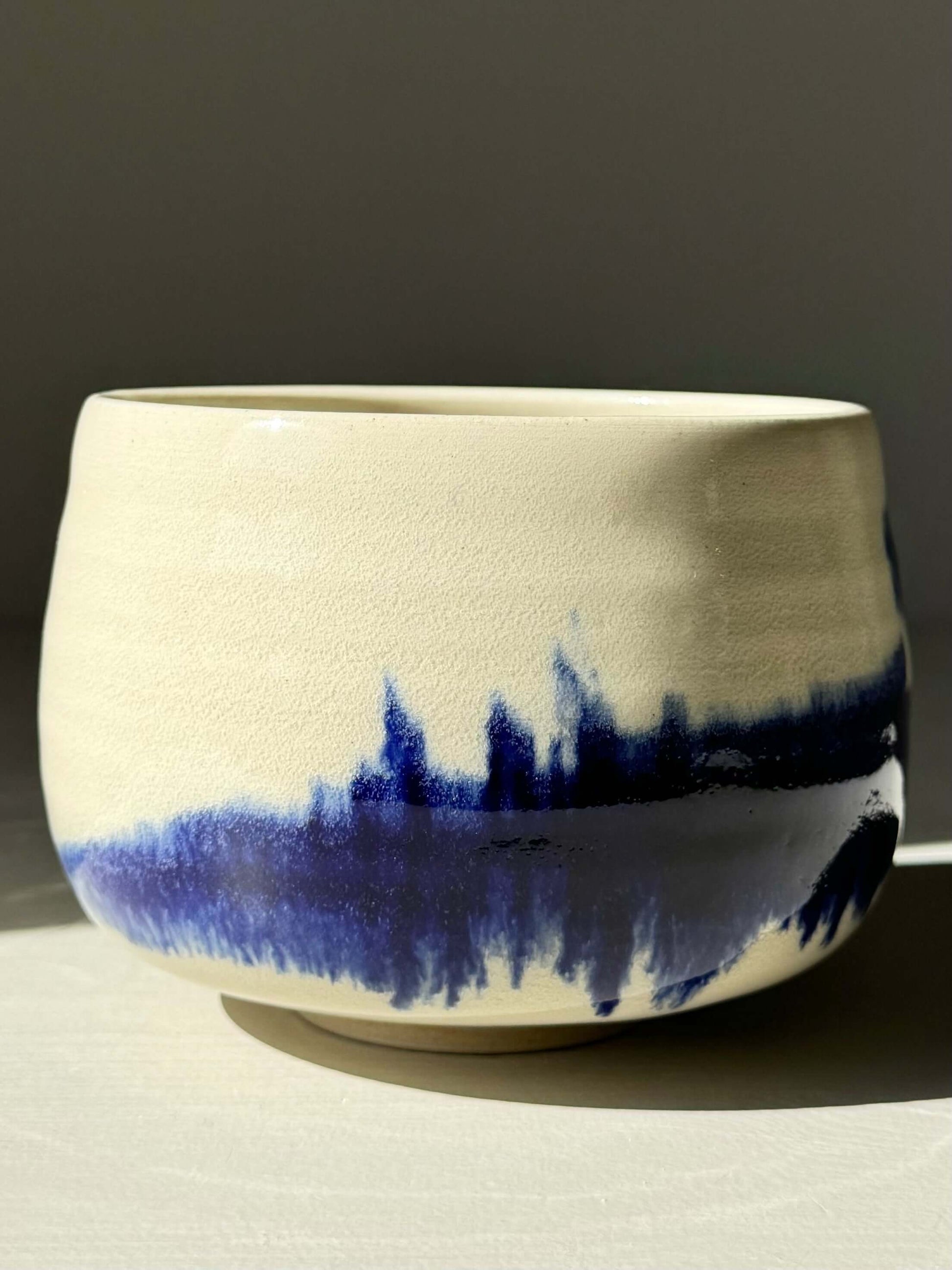 Rounded matcha bowl with cobalt glaze from Gosu Series, featuring deep blue patterns resembling distant trees or peaks, soft rounded shape.