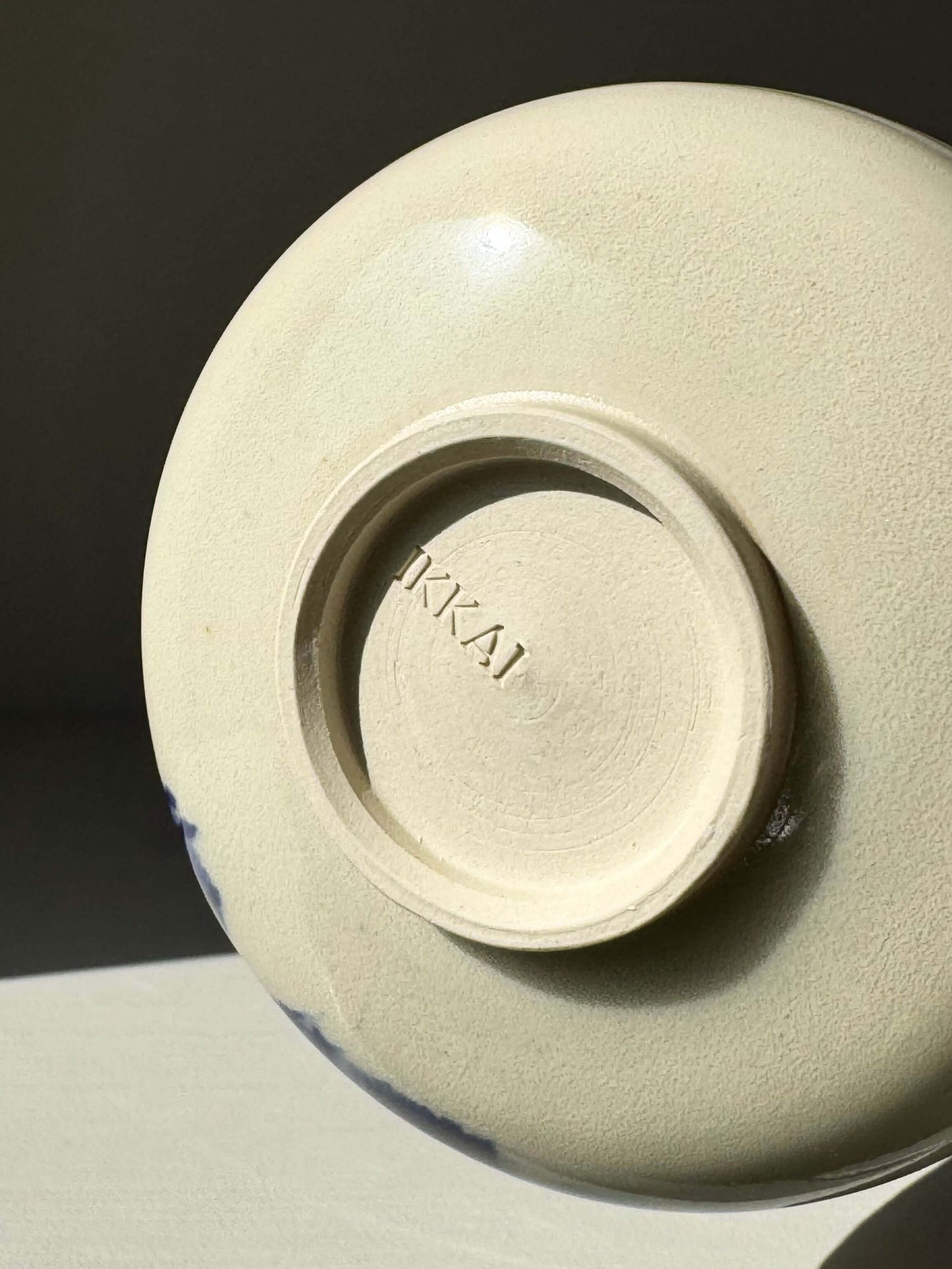 Underside of a rounded matcha bowl from the Gosu Series, featuring a smooth base with a cobalt glaze detail. Modern ceramic design.