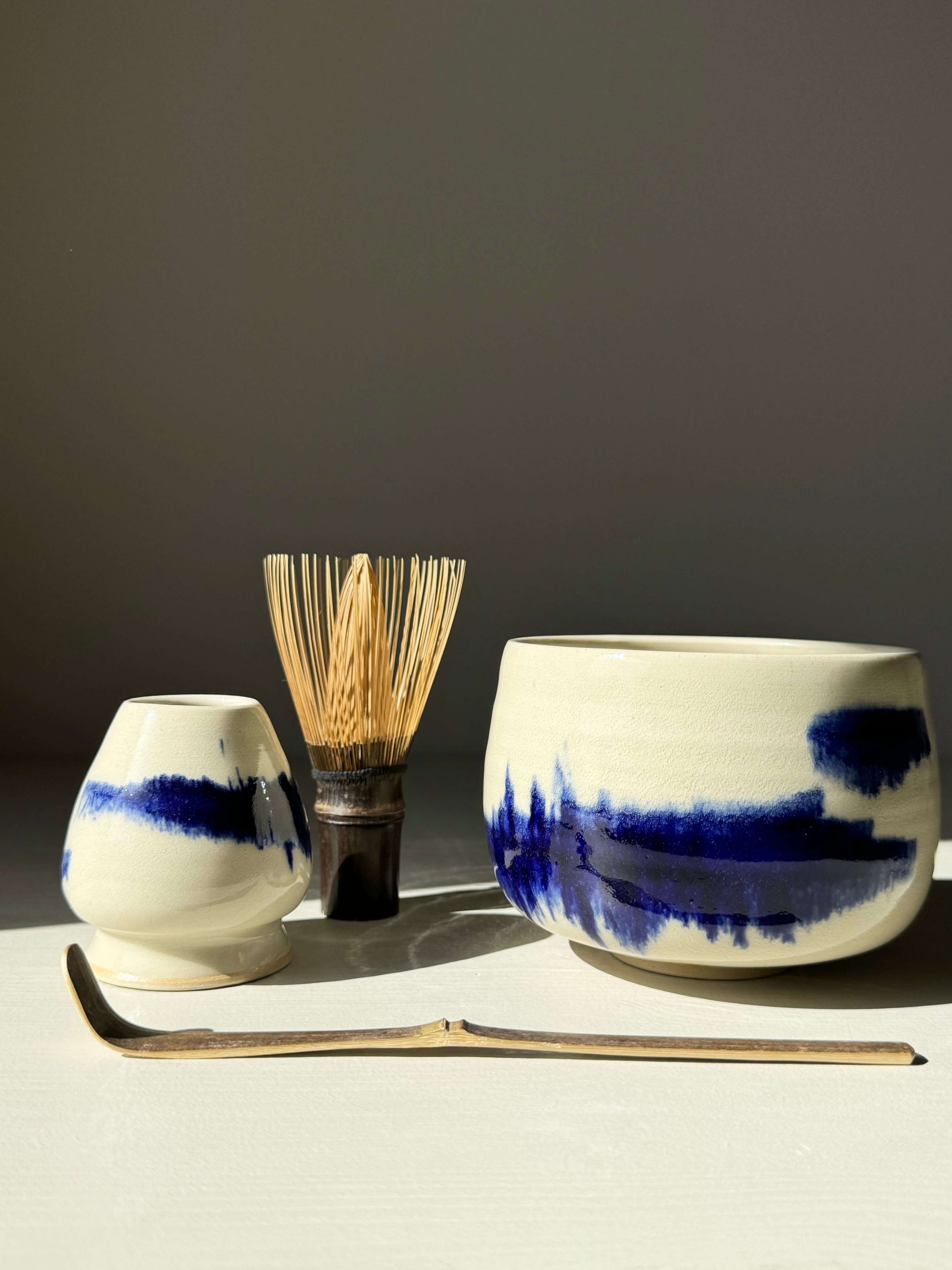 Rounded Matcha Bowl from Gosu Series with cobalt glaze, featuring chasen and scoop on white background.