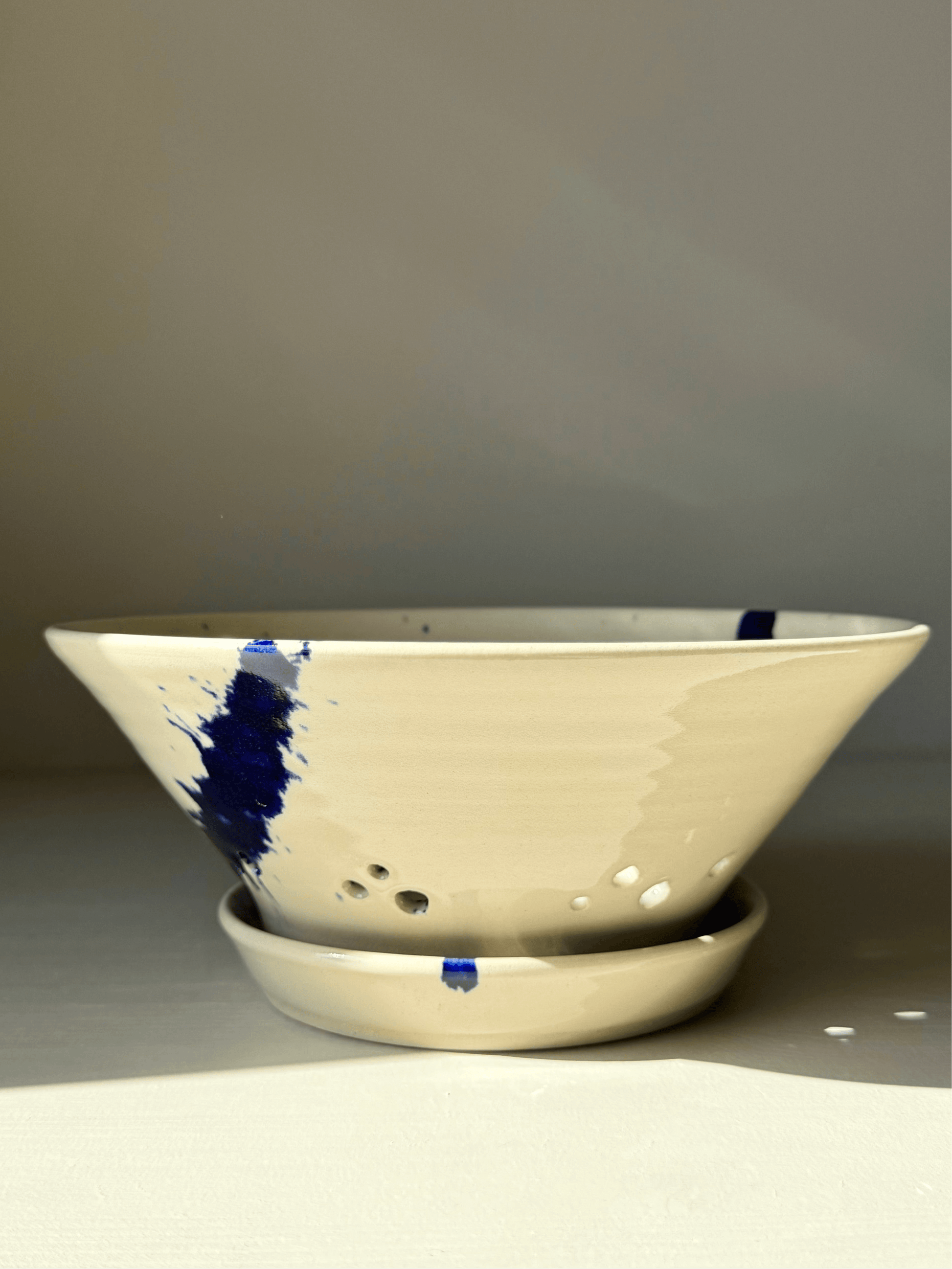 Sculptural berry bowl from the Gosu Series with cobalt blue splashes and matching drip plate, perfect for rinsing fresh fruit.