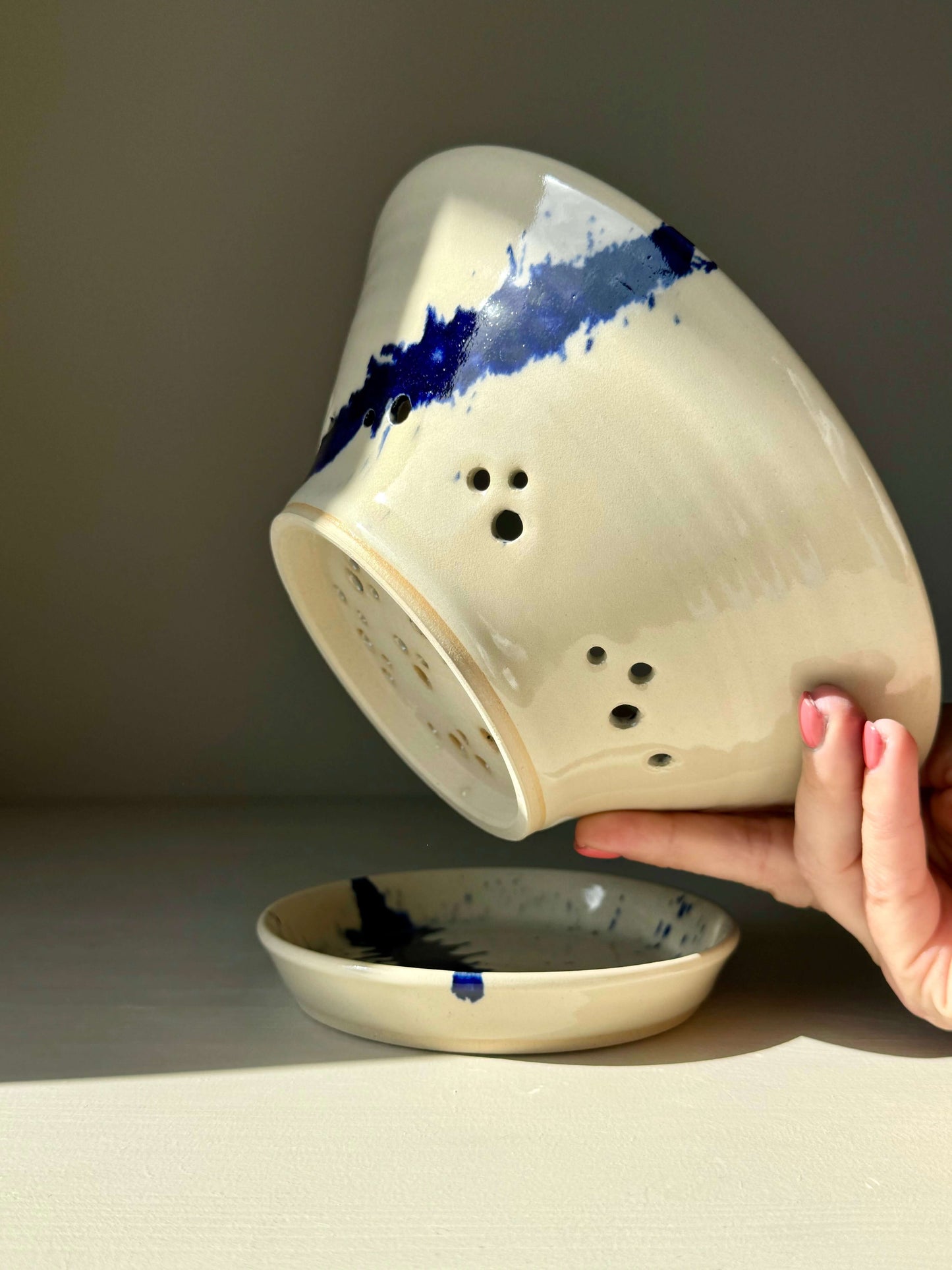 Hand holding Gosu Series Berry Bowl with cobalt blue splashes and matching drip plate, designed for rinsing and serving fresh berries.