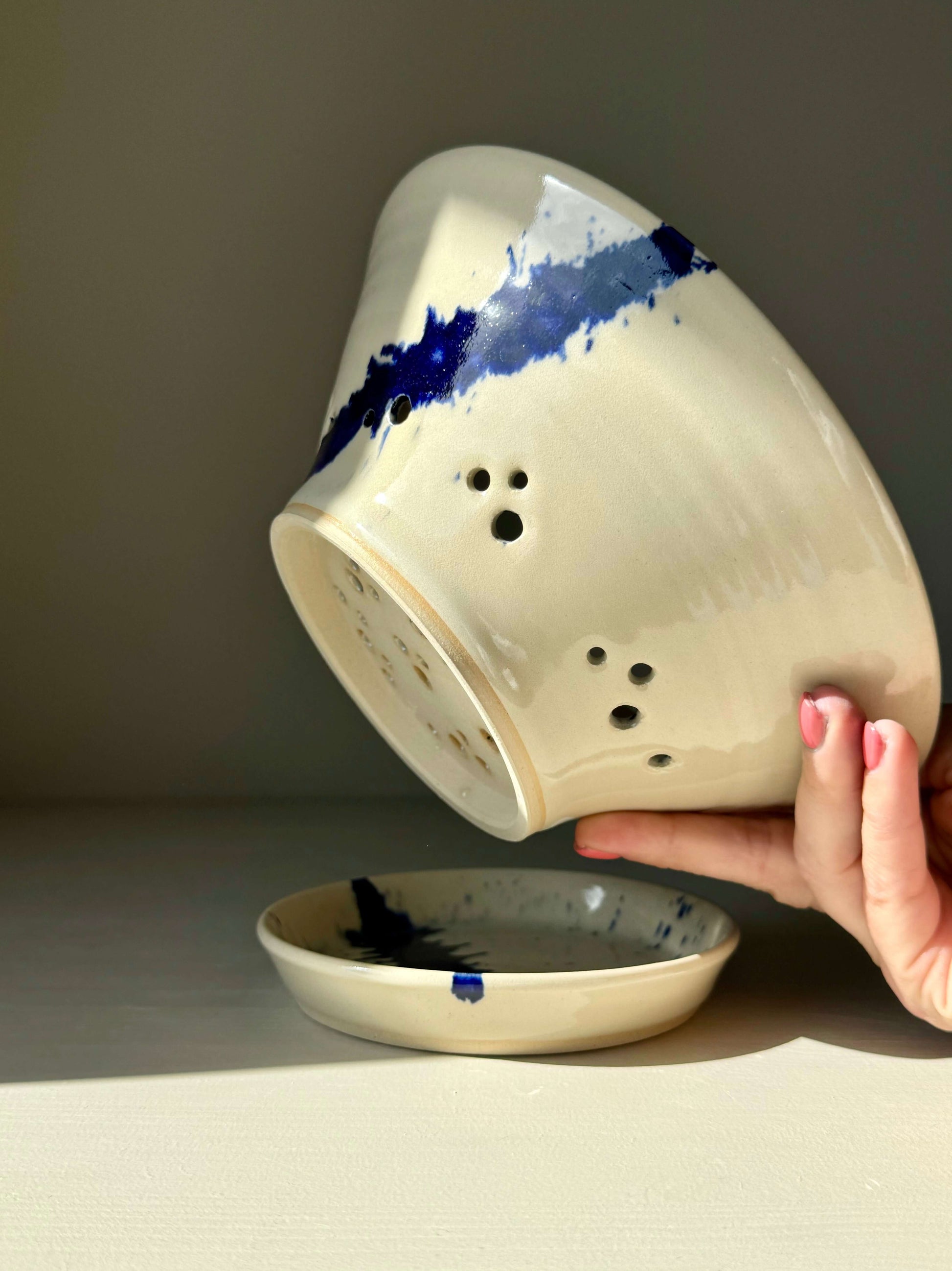 Hand holding Gosu Series Berry Bowl with cobalt blue splashes and matching drip plate, designed for rinsing and serving fresh berries.