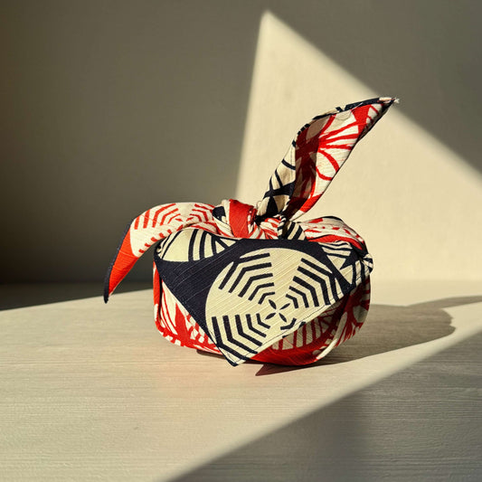 Small navy blue and red furoshiki cloth wrapped gift, inspired by pine trees, symbolizing longevity and resilience in Japanese culture.