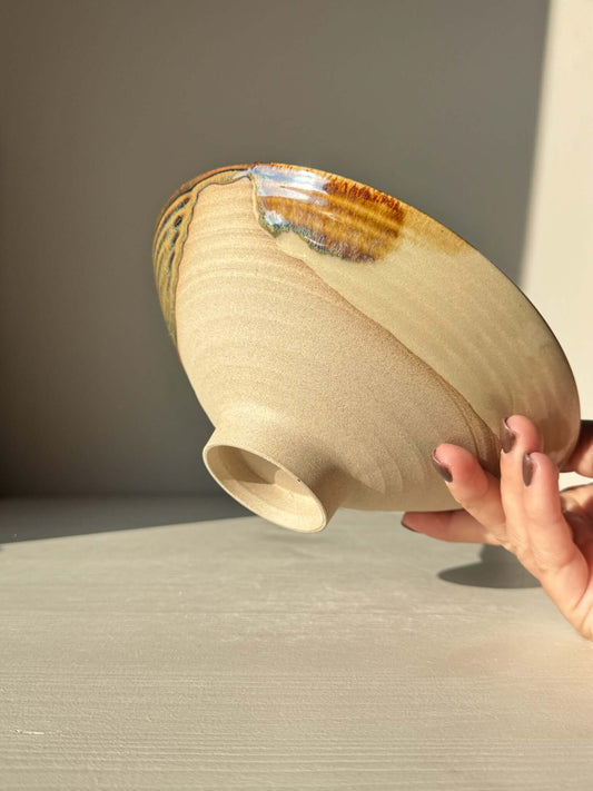 Hand holding a Small Serving Bowl - Inyo Series #01, featuring handmade ceramic with tenmoku, amber, and blue glazes over raw clay base.