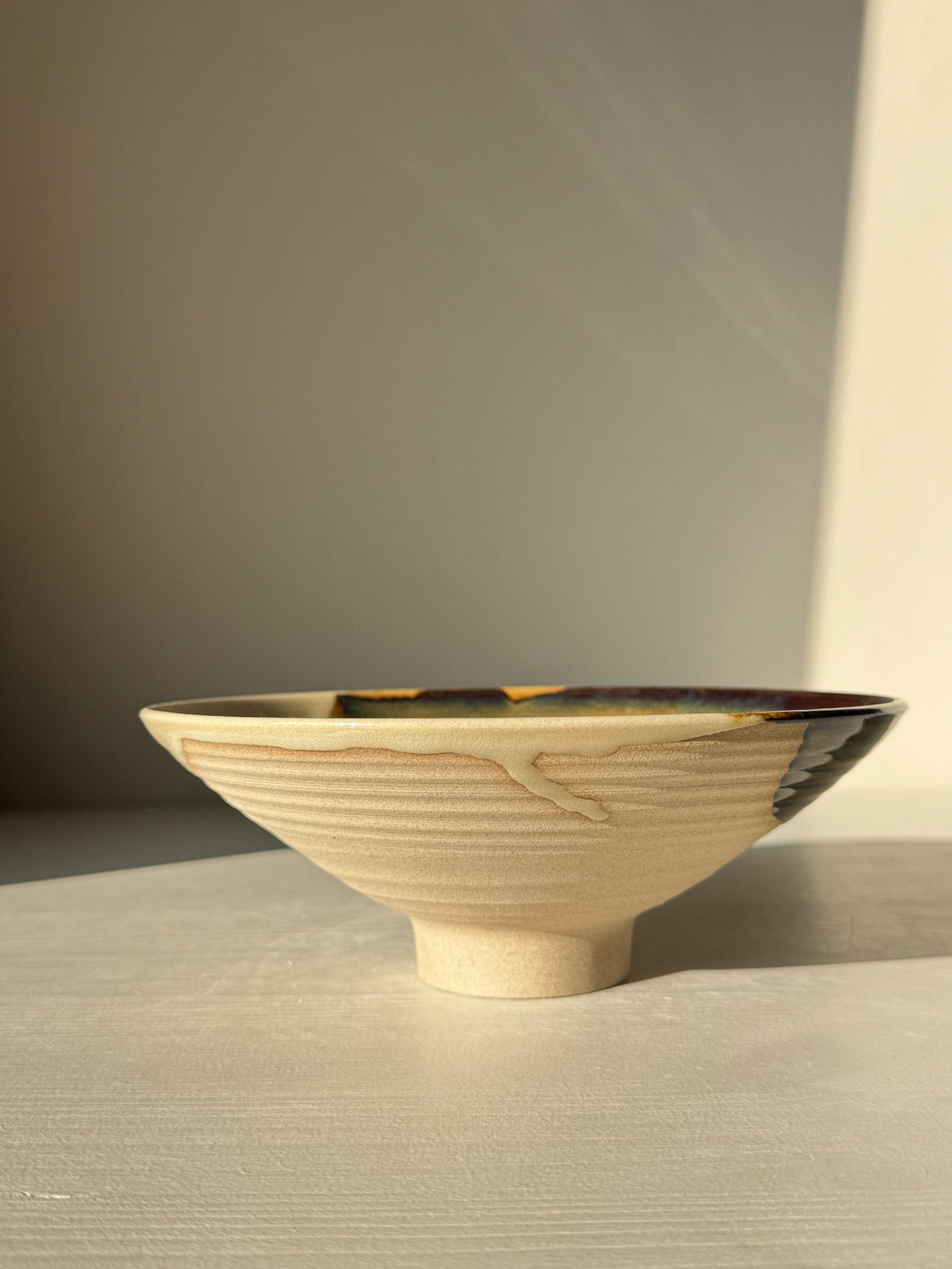 Handmade ceramic Small Serving Bowl - Inyo Series #01 with tenmoku and golden amber glazes, displaying unique color contrasts.