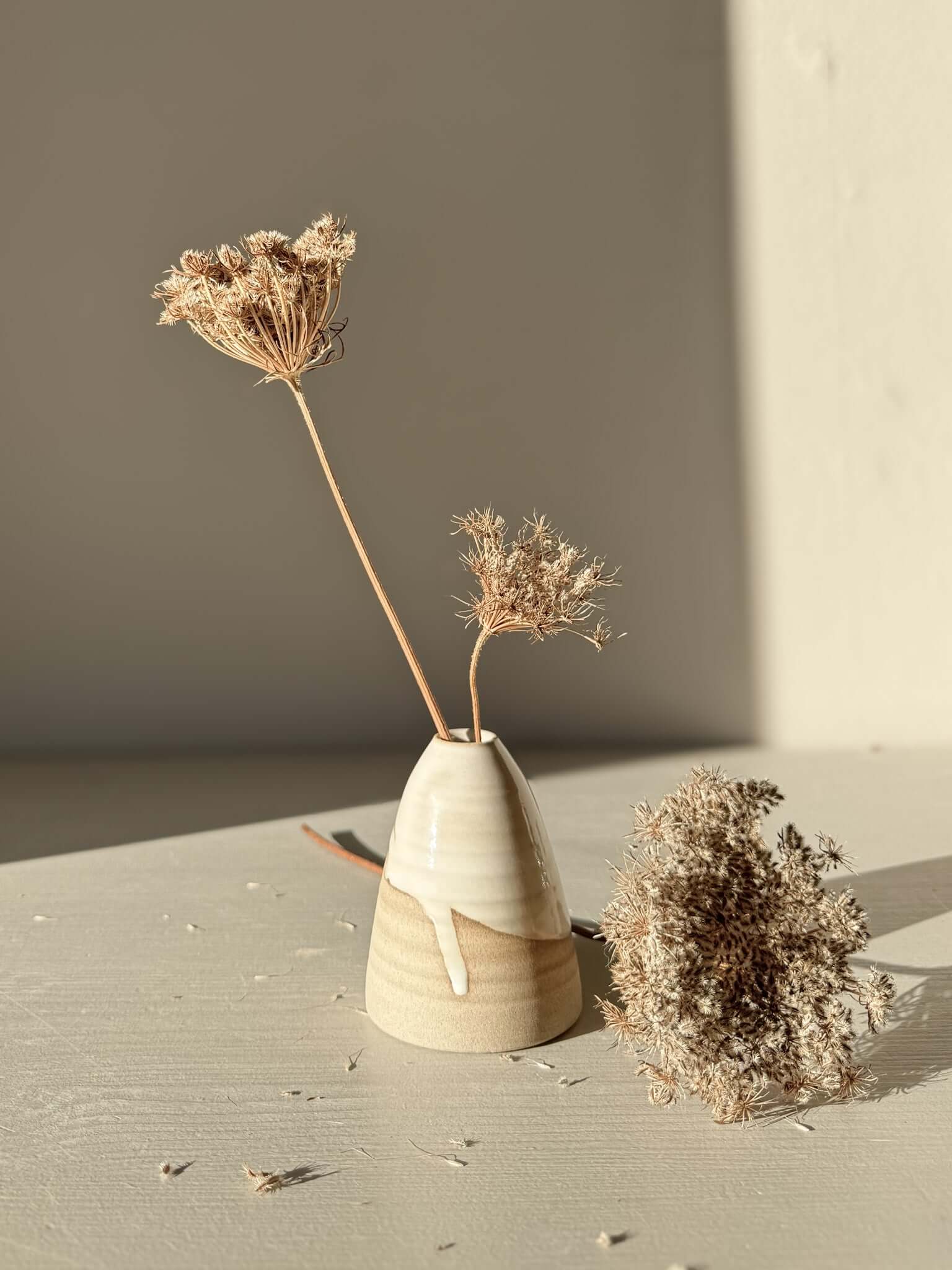 Small Vase – Yuki #01 with gentle curves and white glaze on warm clay, showcasing dried flowers in a serene setting