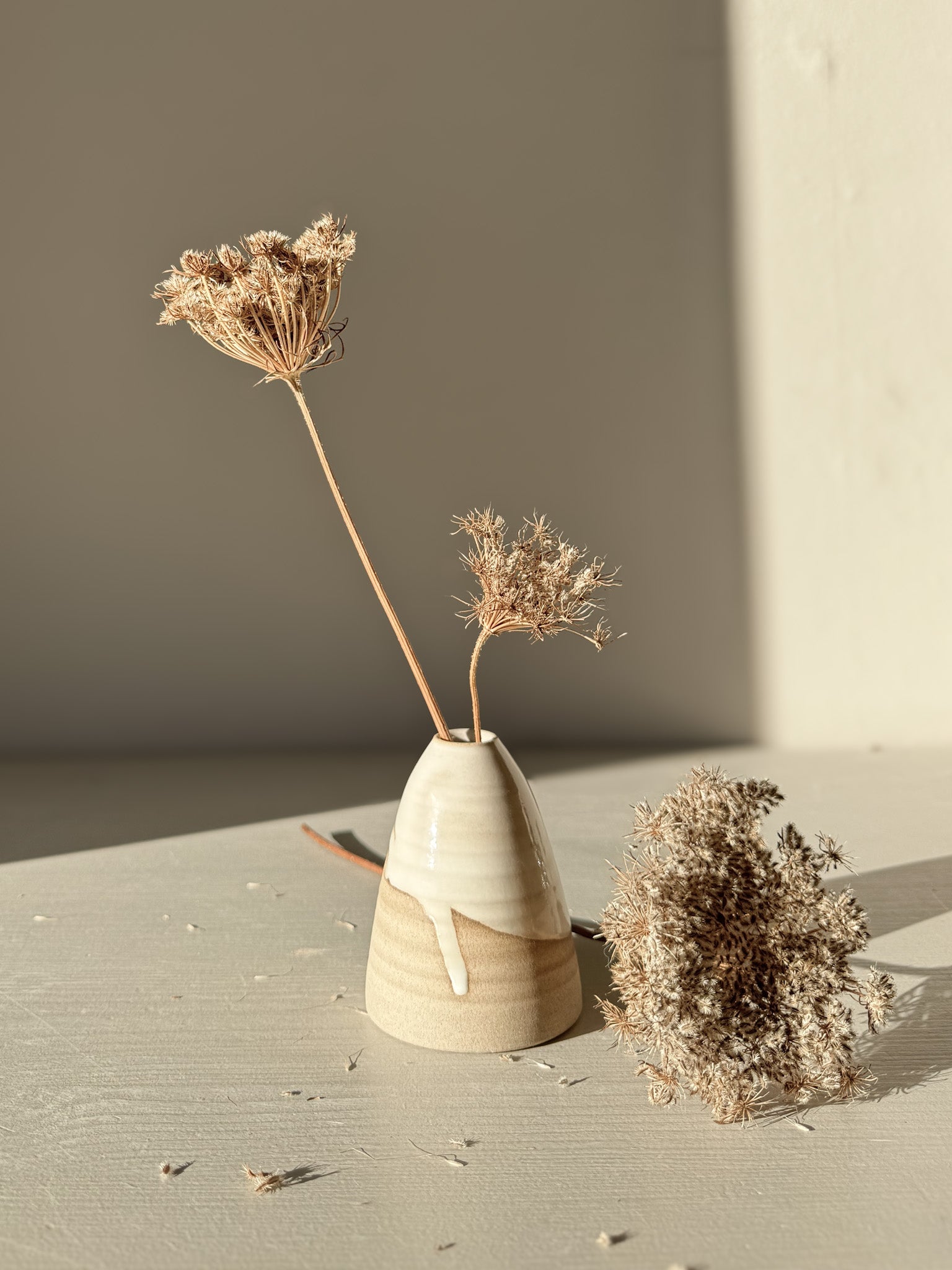 Small Vase – Yuki #01 with gentle curves and white glaze on warm clay, showcasing dried flowers in a serene setting