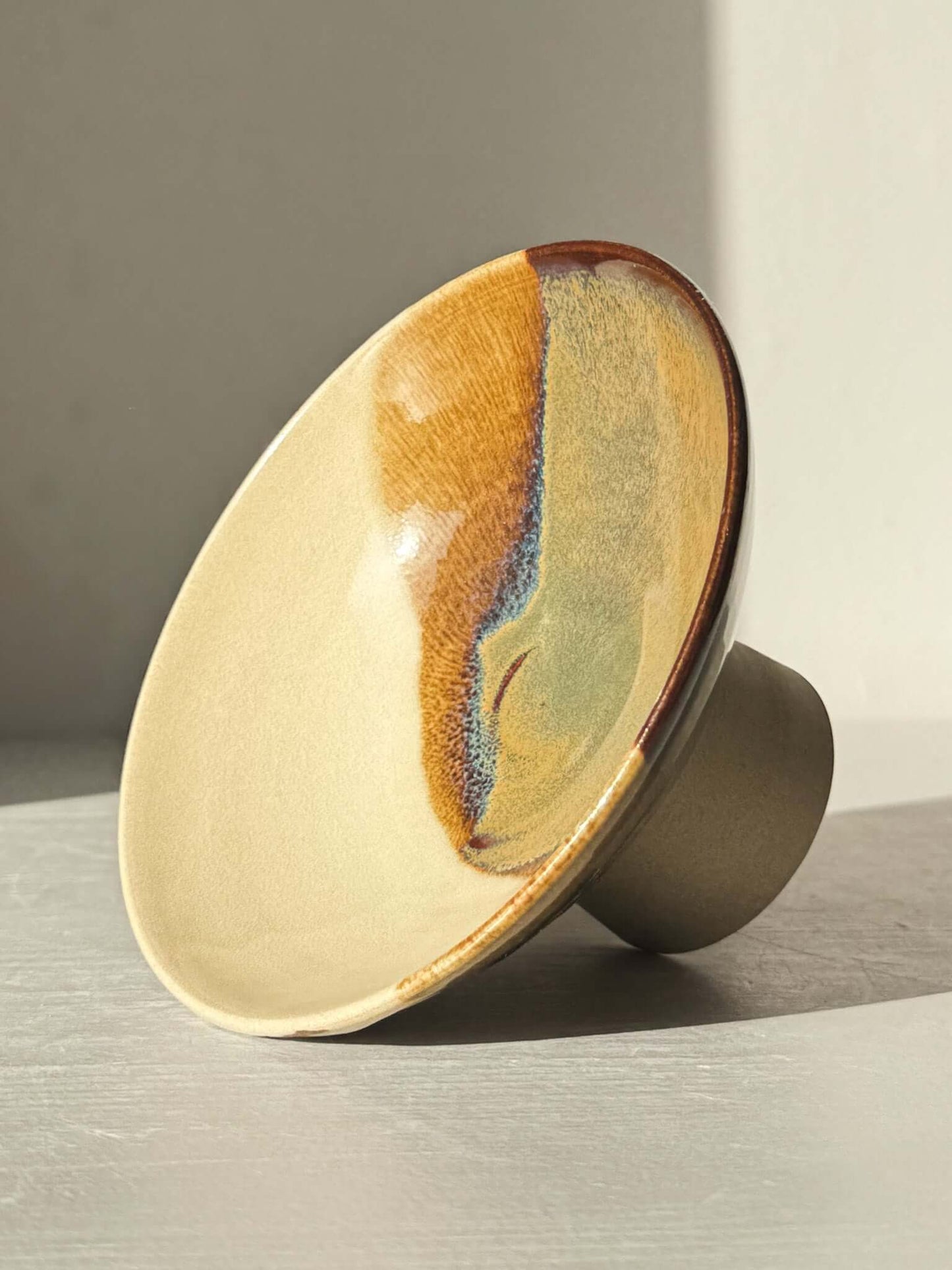 Small Pedestal Bowl - Inyo #01 with warm gold, rich brown, blue, and green glazes on display, elegant and sculptural design.