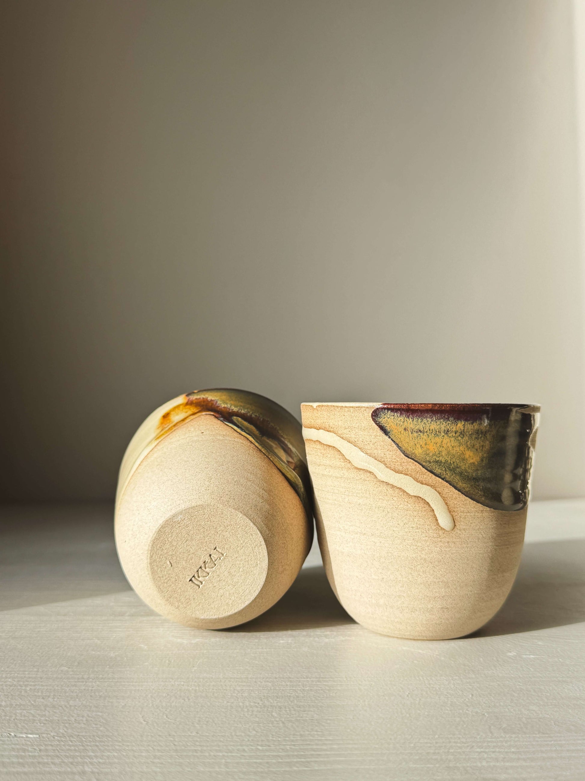 Pair of Stackable Latte Cups - Inyo with unique tenmoku and clear glaze design on a table