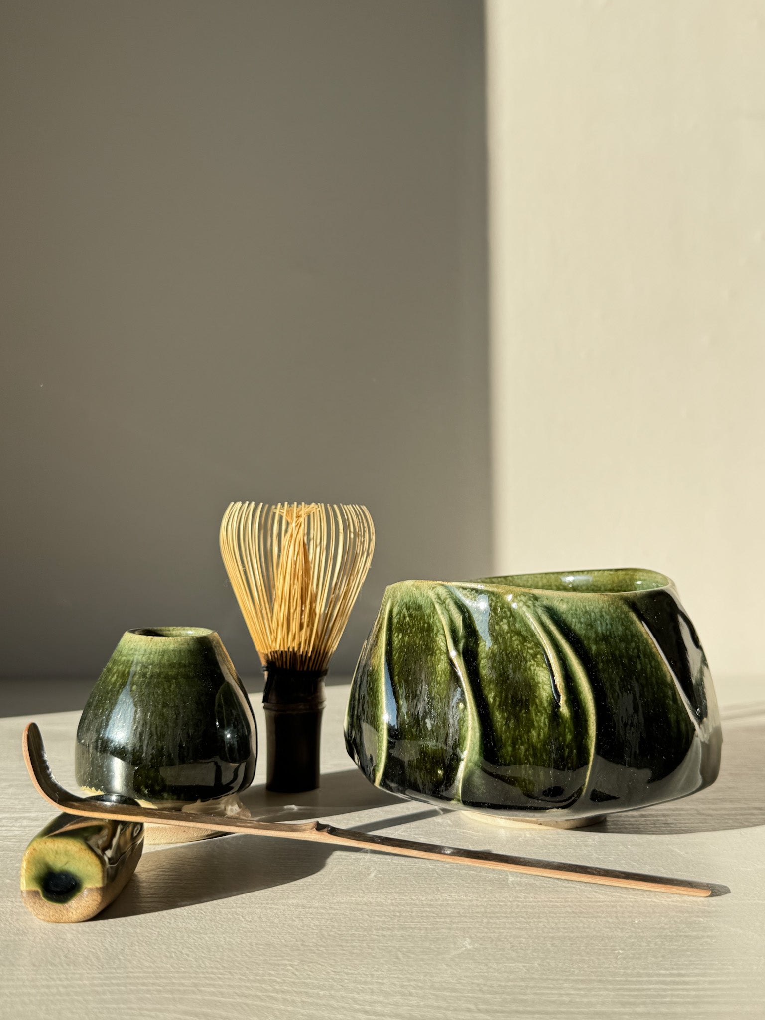 Textured Matcha Bowl - Hinoki #14 with green glaze and bamboo whisk, showcasing natural beauty and craftsmanship in a serene setting.