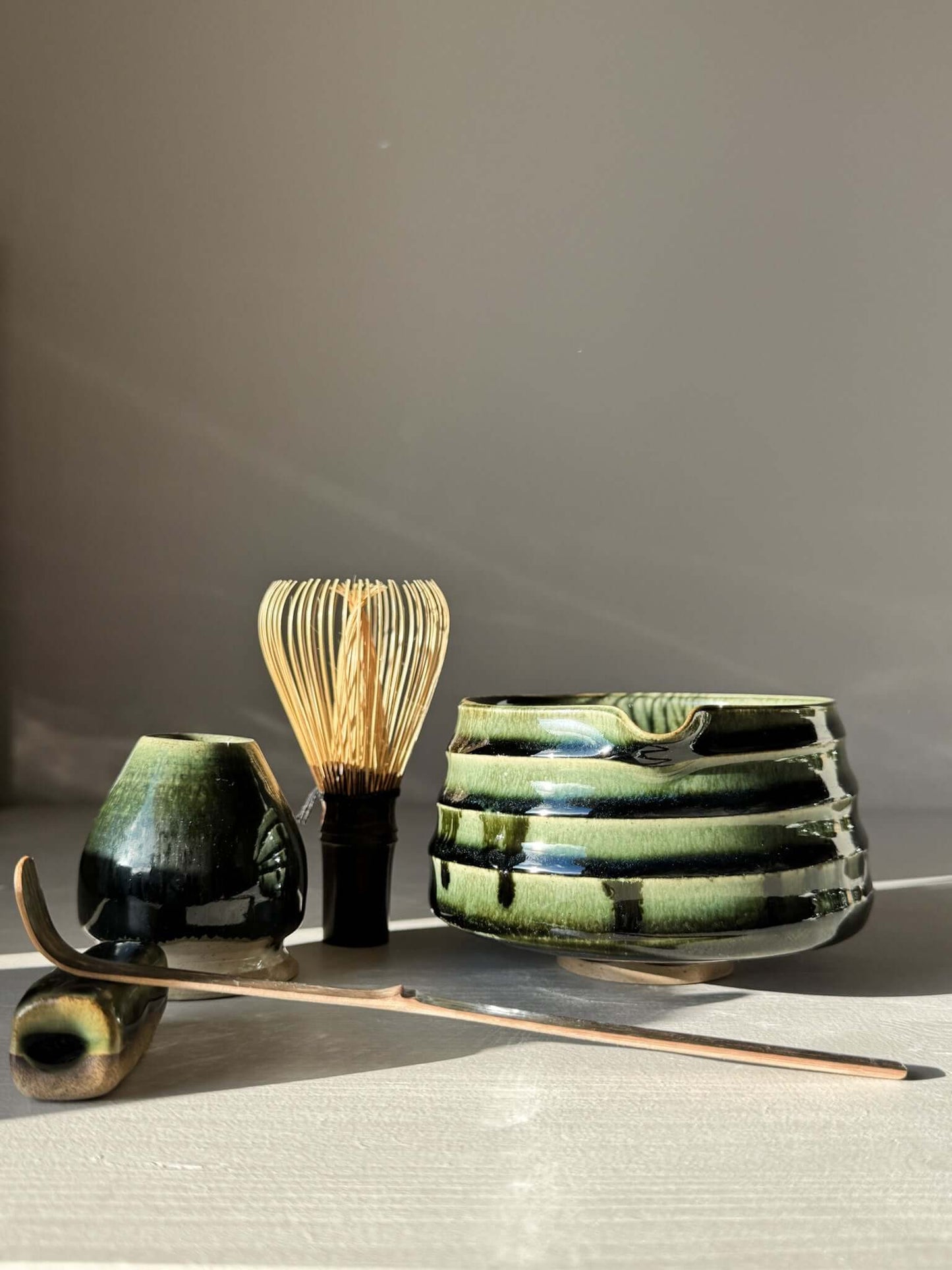 Textured Matcha Bowl Spout - Hinoki #03 with glossy green glaze, surrounded by tea utensils in a serene setting.