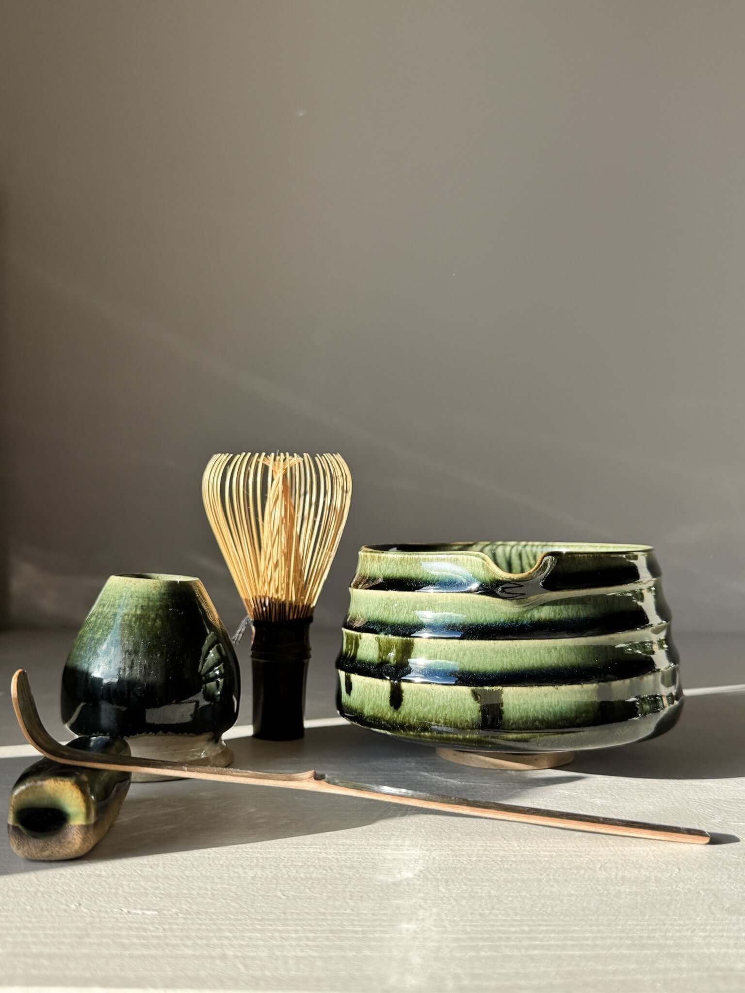 Textured Matcha Bowl Spout - Hinoki #03 with glossy green glaze, surrounded by tea utensils in a serene setting.