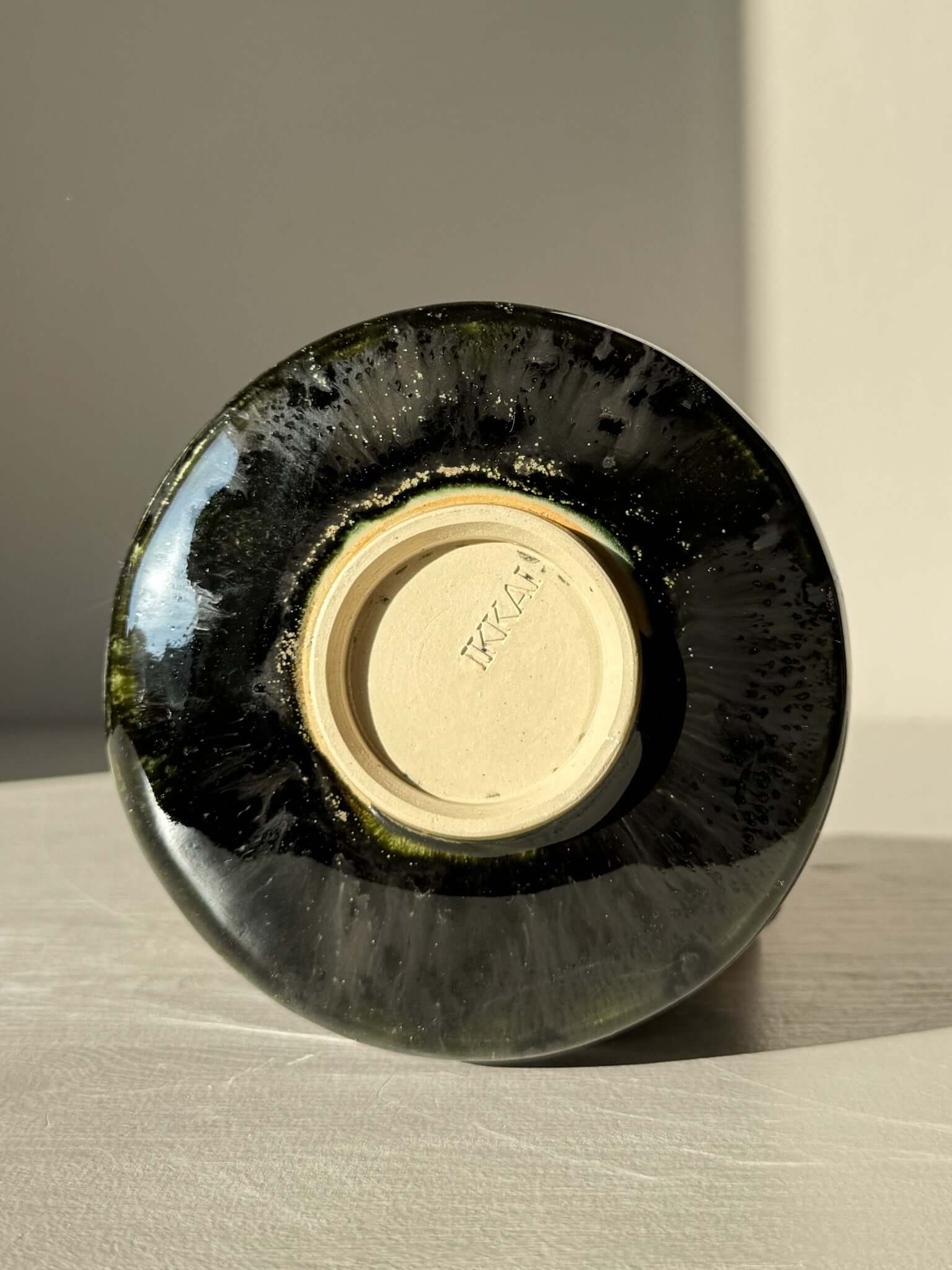 Underside view of Textured Matcha Bowl Spout - Hinoki #04 with glossy green glaze and signature, highlighting the craftsmanship details.