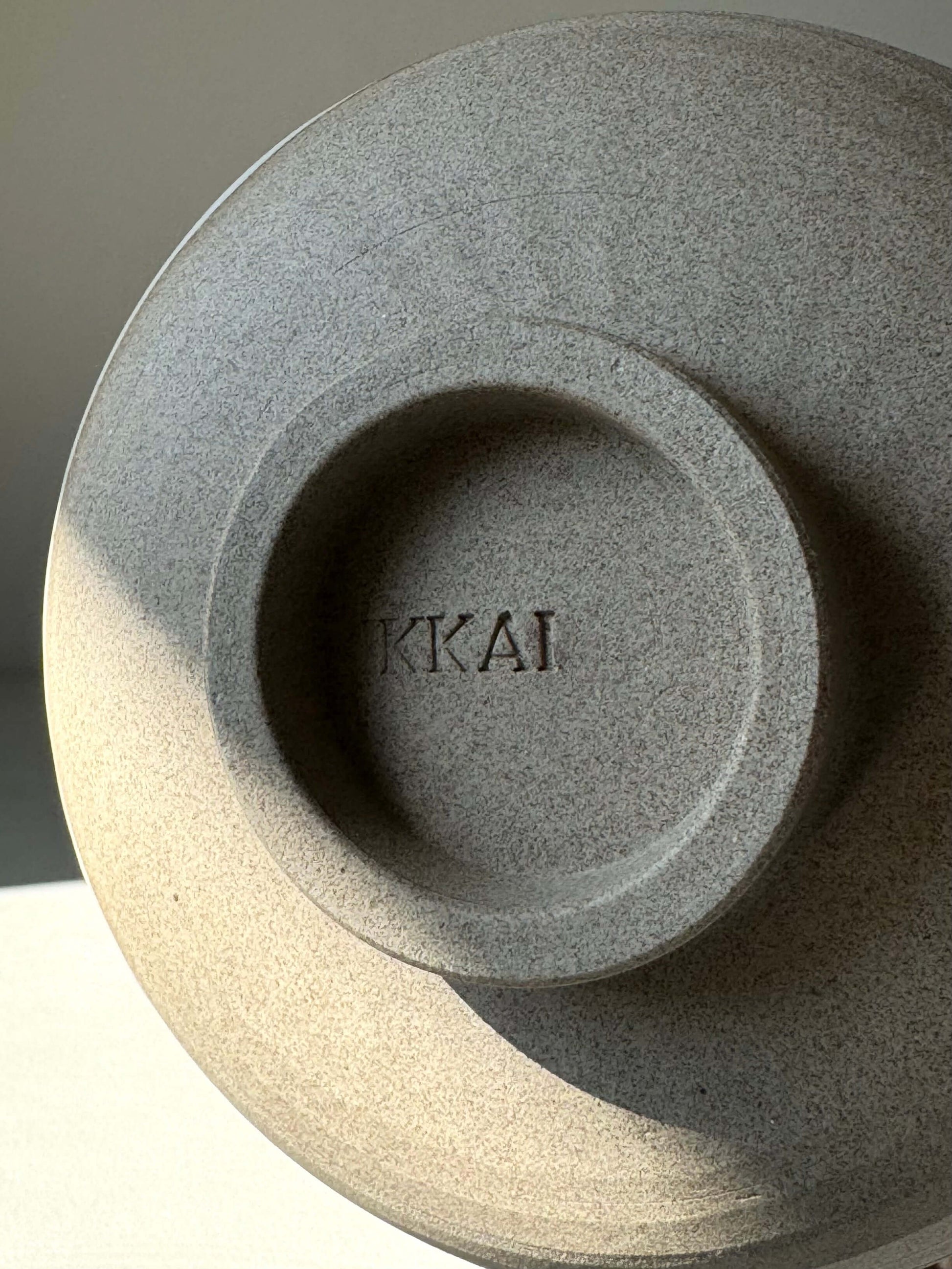 Close-up of the base of a textured matcha bowl with 'KKAI' engraved, highlighting its handcrafted design.