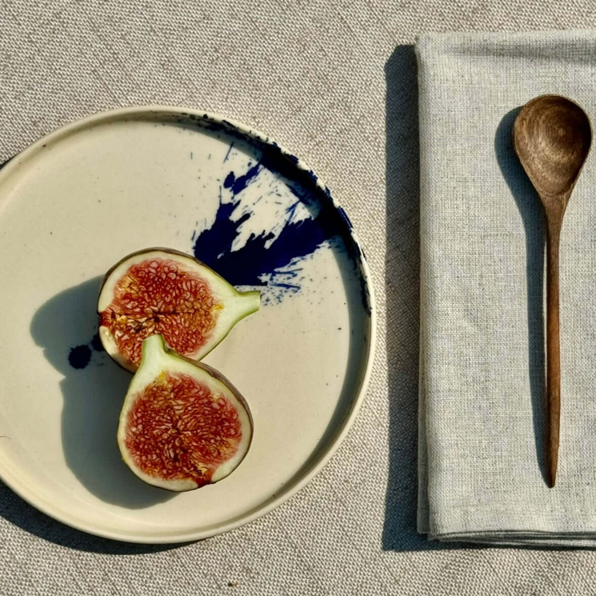 Medium wooden spoons beside handmade ceramic plate with figs