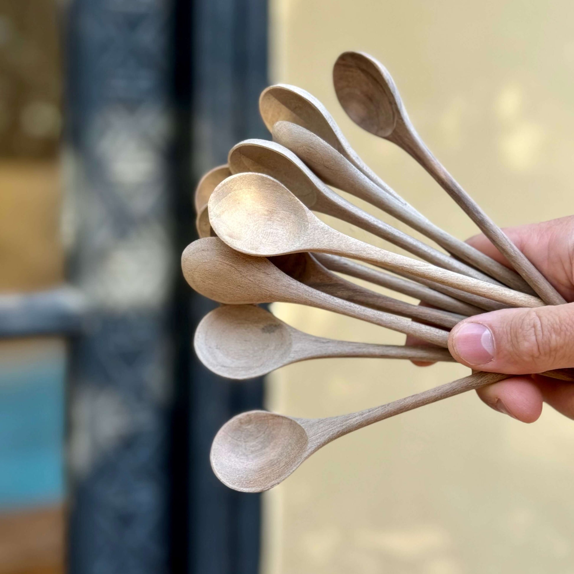 Hand holding handmade wooden tea spoons crafted from walnut wood