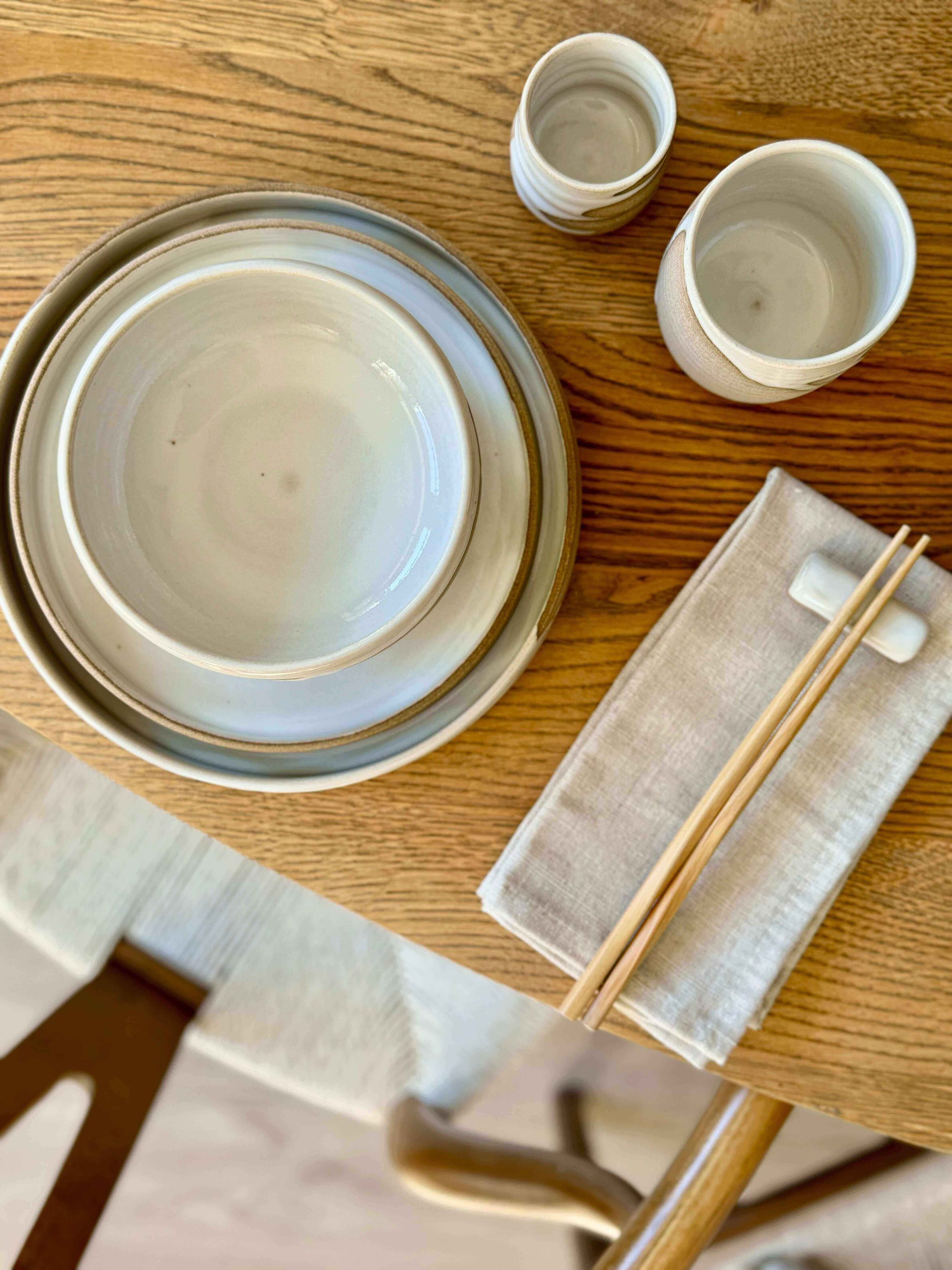 Yuki Series chopstick and matcha spoon rest on a wooden table with ceramic plates and cups.